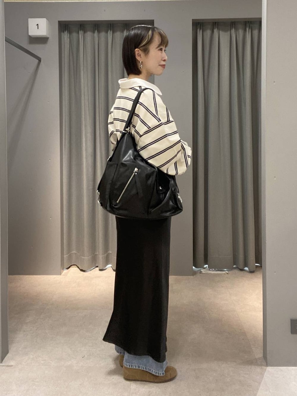 ブラック系のショルダーバッグ、ブルー系のデニムパンツ、ブラウン系のスニーカーを着用したレディースの春コーディネートの2枚目の写真