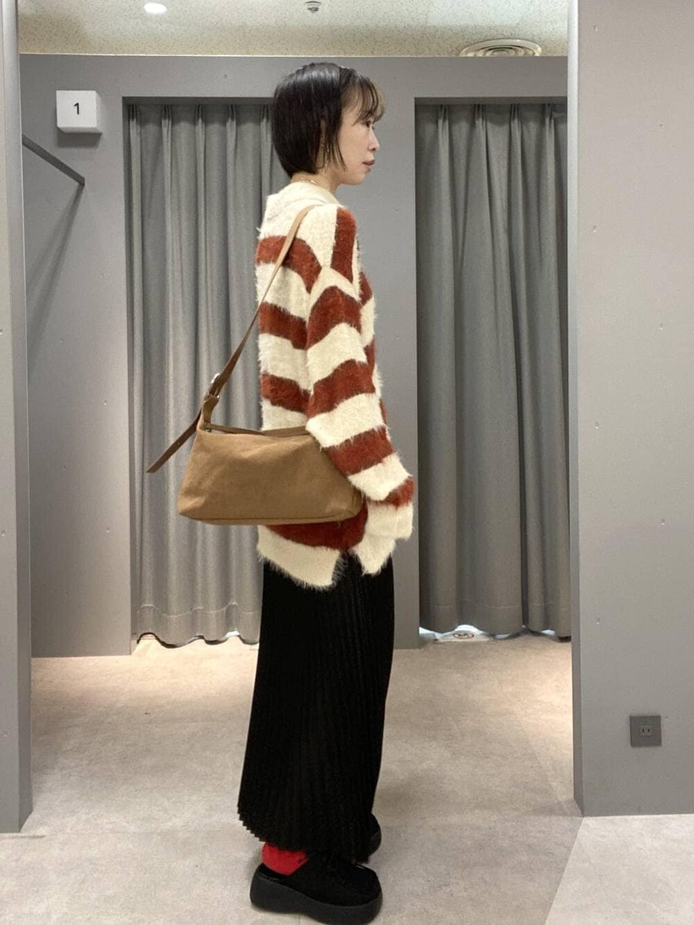 ブラウン系のショルダーバッグ、ブラック系のスカート、ブラック系のその他シューズを着用したレディースの冬コーディネートの2枚目の写真