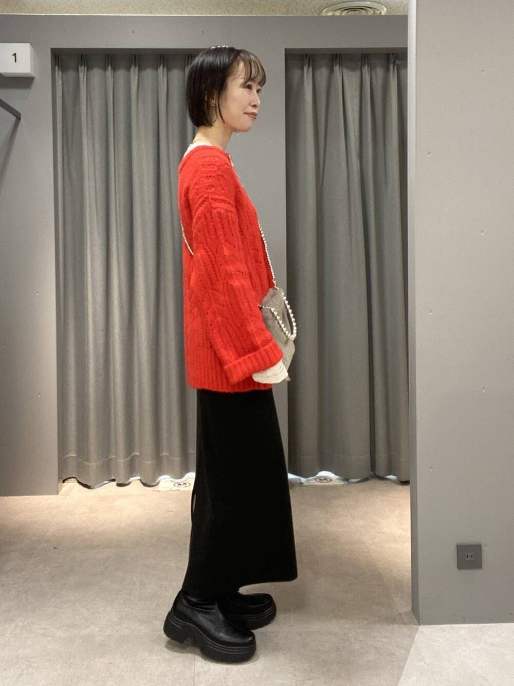 ホワイト系のTシャツ/カットソー、ブラック系のスカート、ブラック系のブーツを着用したレディースの冬コーディネートの2枚目の写真