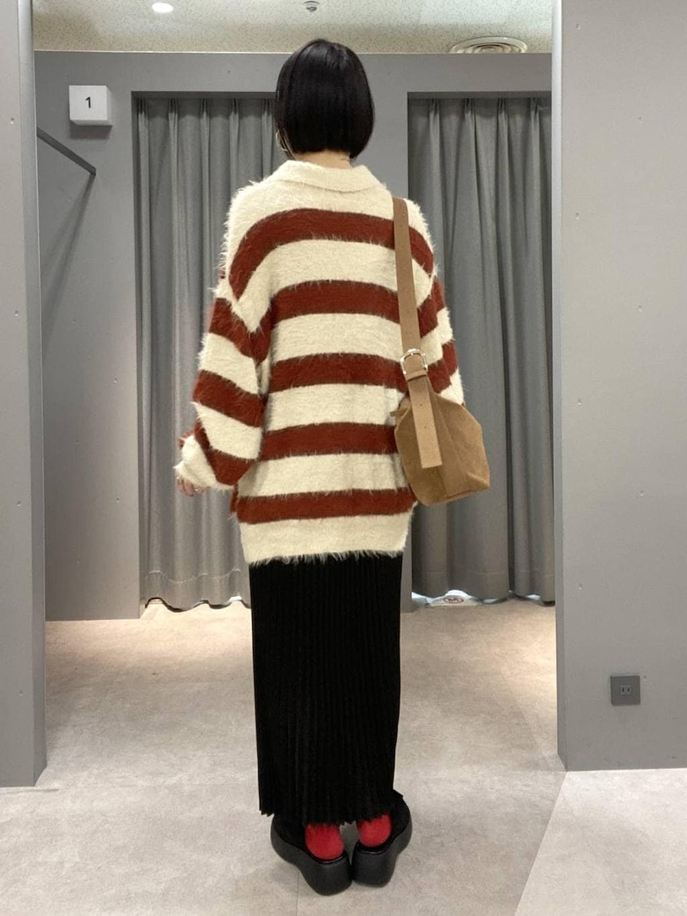 ブラウン系のショルダーバッグ、ブラック系のスカート、ブラック系のその他シューズを着用したレディースの冬コーディネートの3枚目の写真