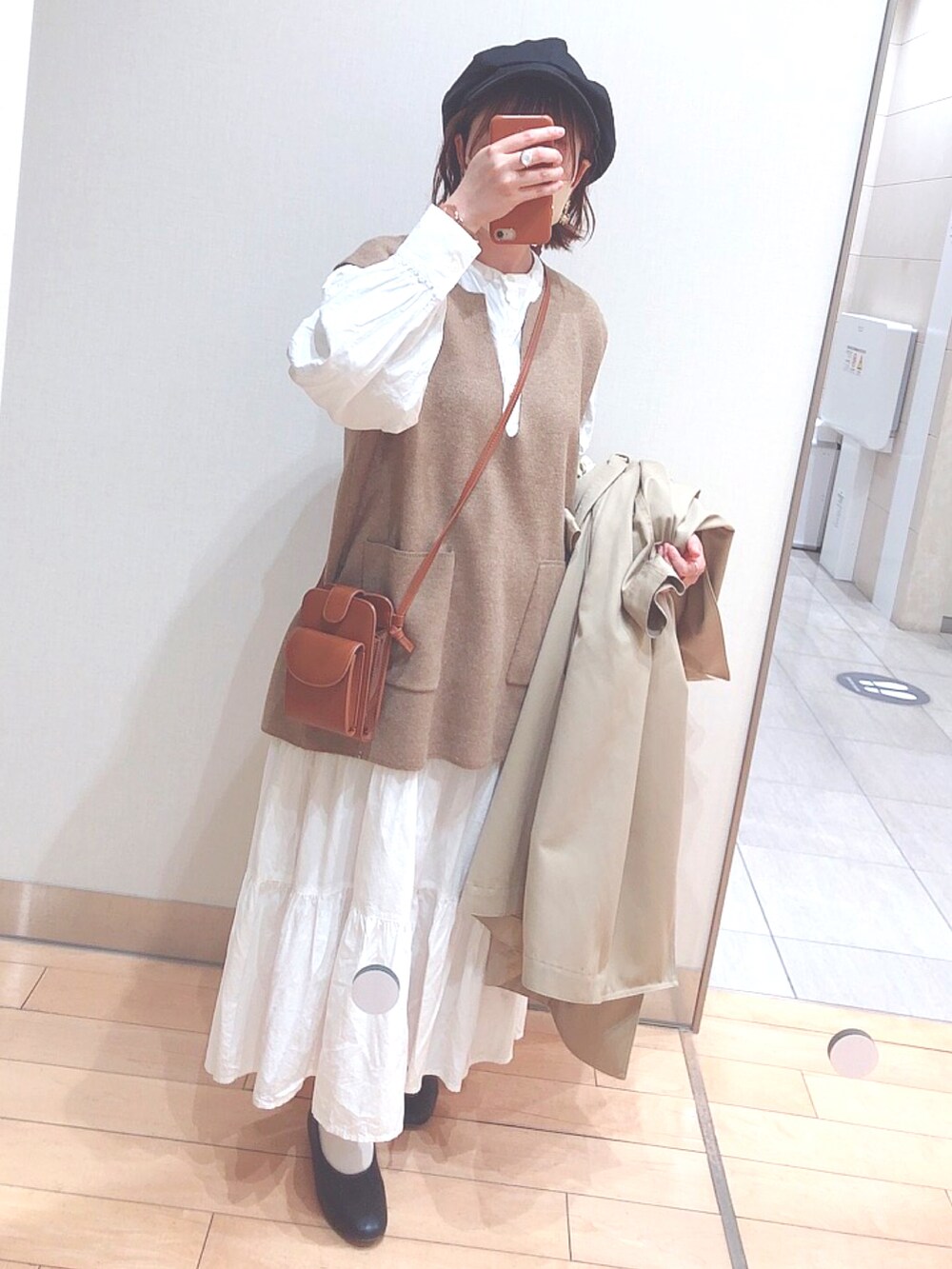 ベージュ系のトレンチコート、ブラウン系のショルダーバッグ、ホワイト系のバッグを着用したレディースの春コーディネートの2枚目の写真