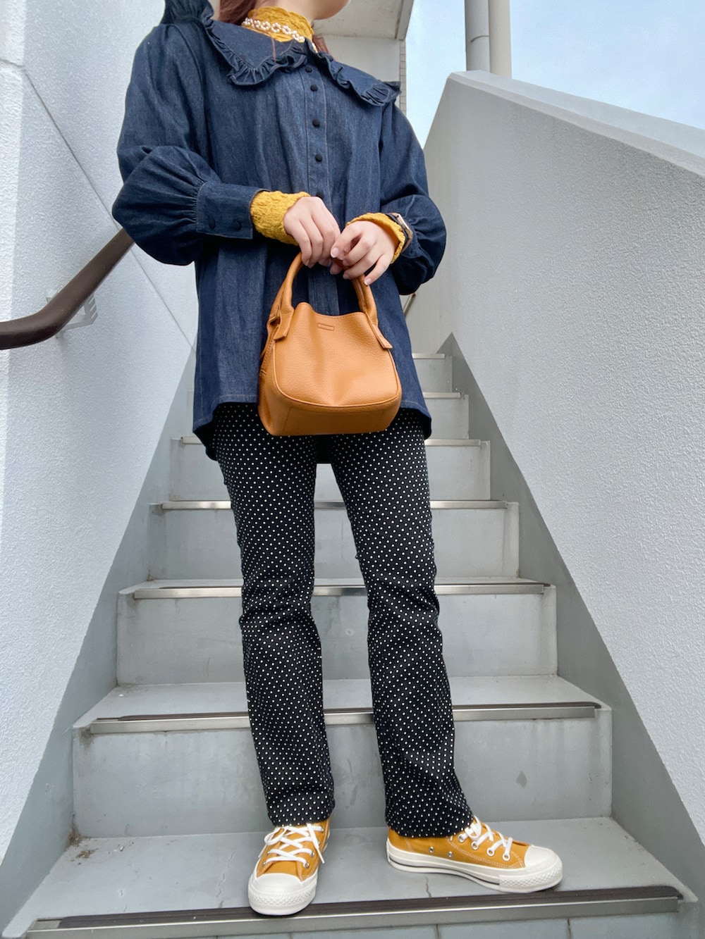 ブラック系のその他パンツ、イエロー系のスニーカー、ブラウン系のハンドバッグを着用したレディースの春コーディネートの2枚目の写真