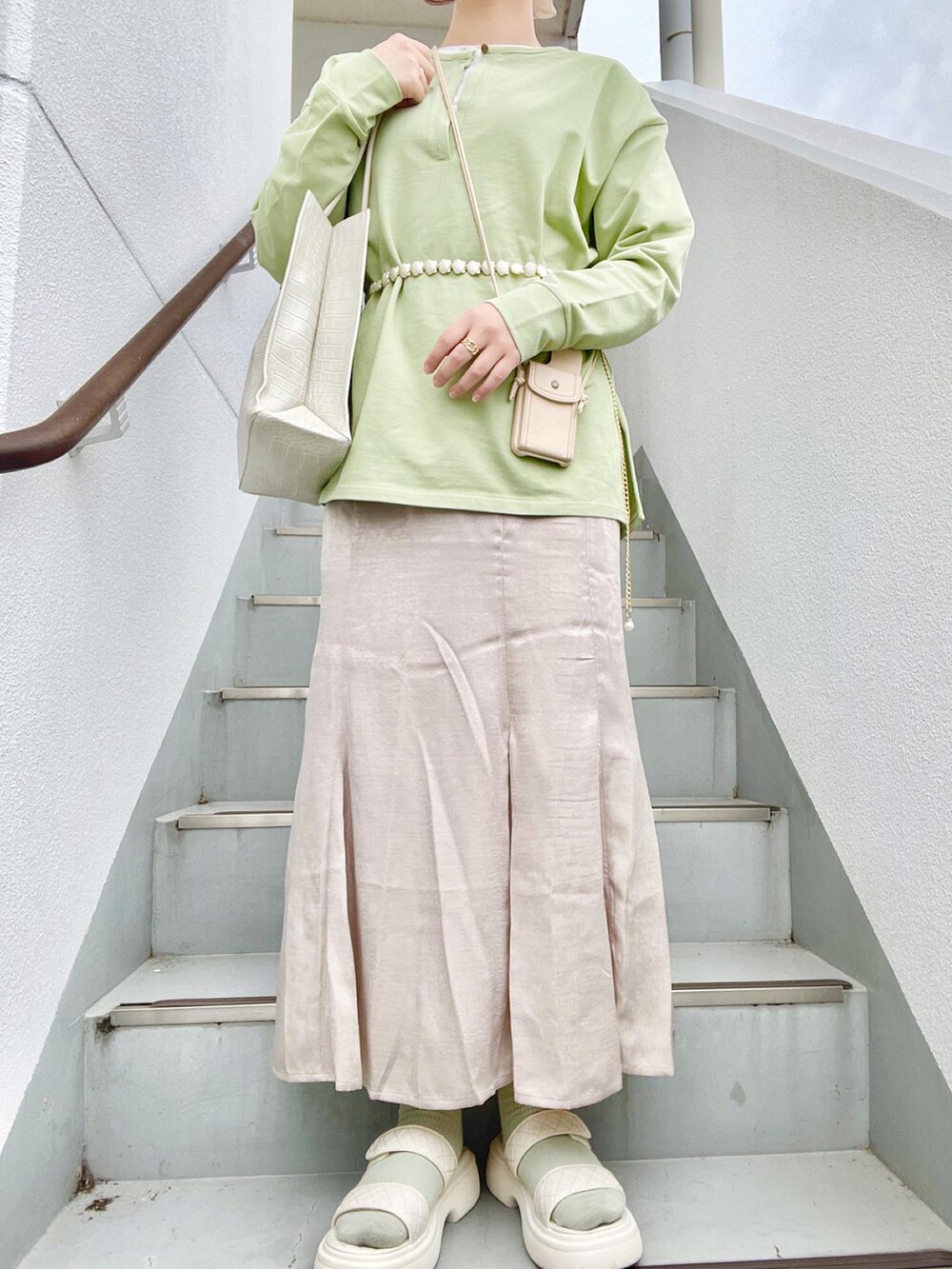 ベージュ系のワンピース、ホワイト系のサンダル、グリーン系のTシャツ/カットソーを着用したレディースの春コーディネートの2枚目の写真