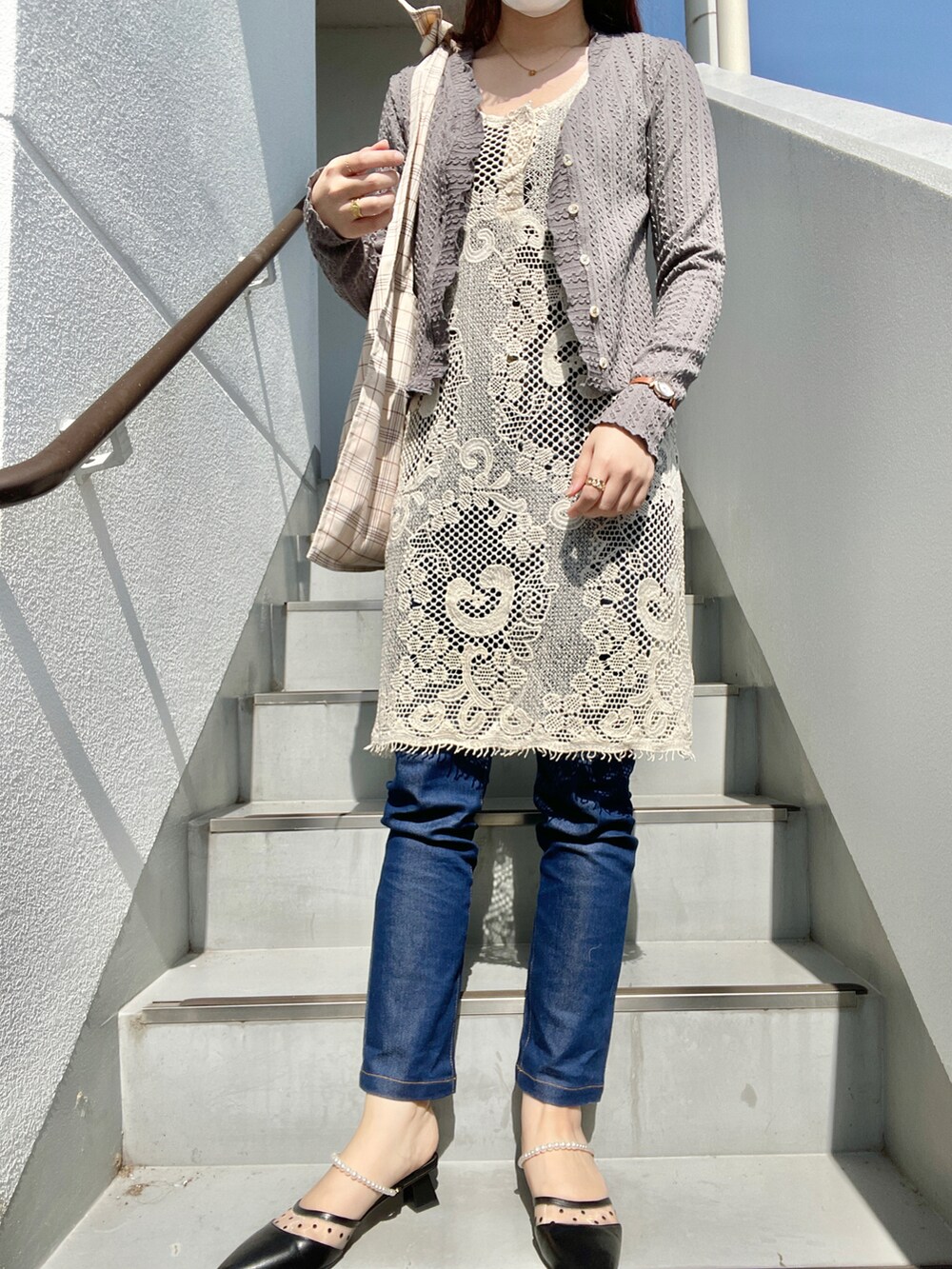 ブルー系のデニムパンツ、ブラック系のパンプス、ベージュ系のワンピースを着用したレディースの春コーディネートの2枚目の写真