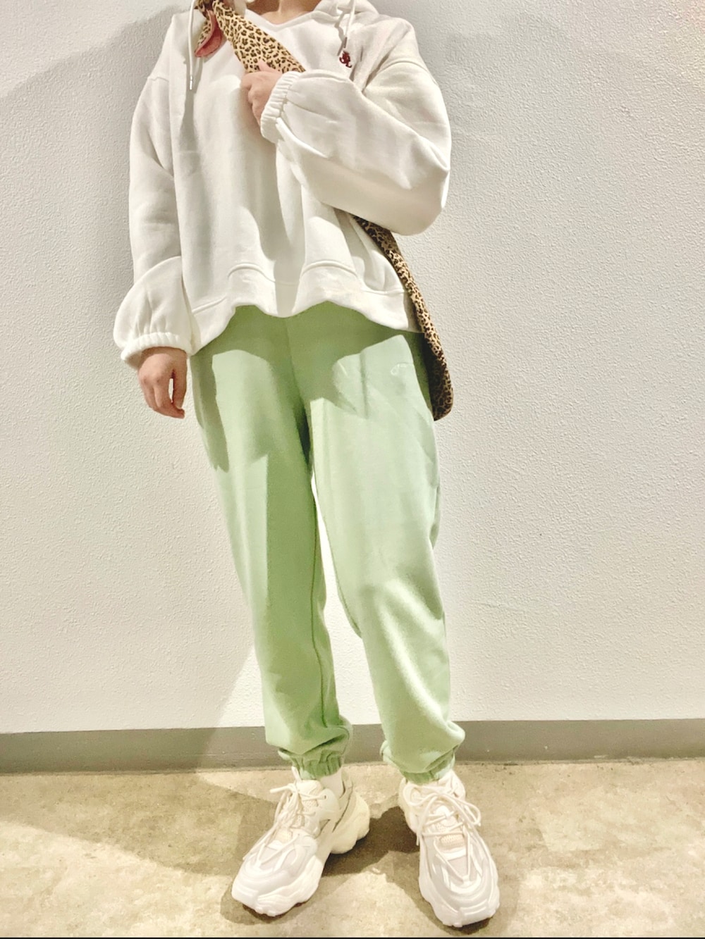 グリーン系のスウェットパンツ、ホワイト系のスニーカー、その他のショルダーバッグを着用したレディースの春コーディネートの2枚目の写真