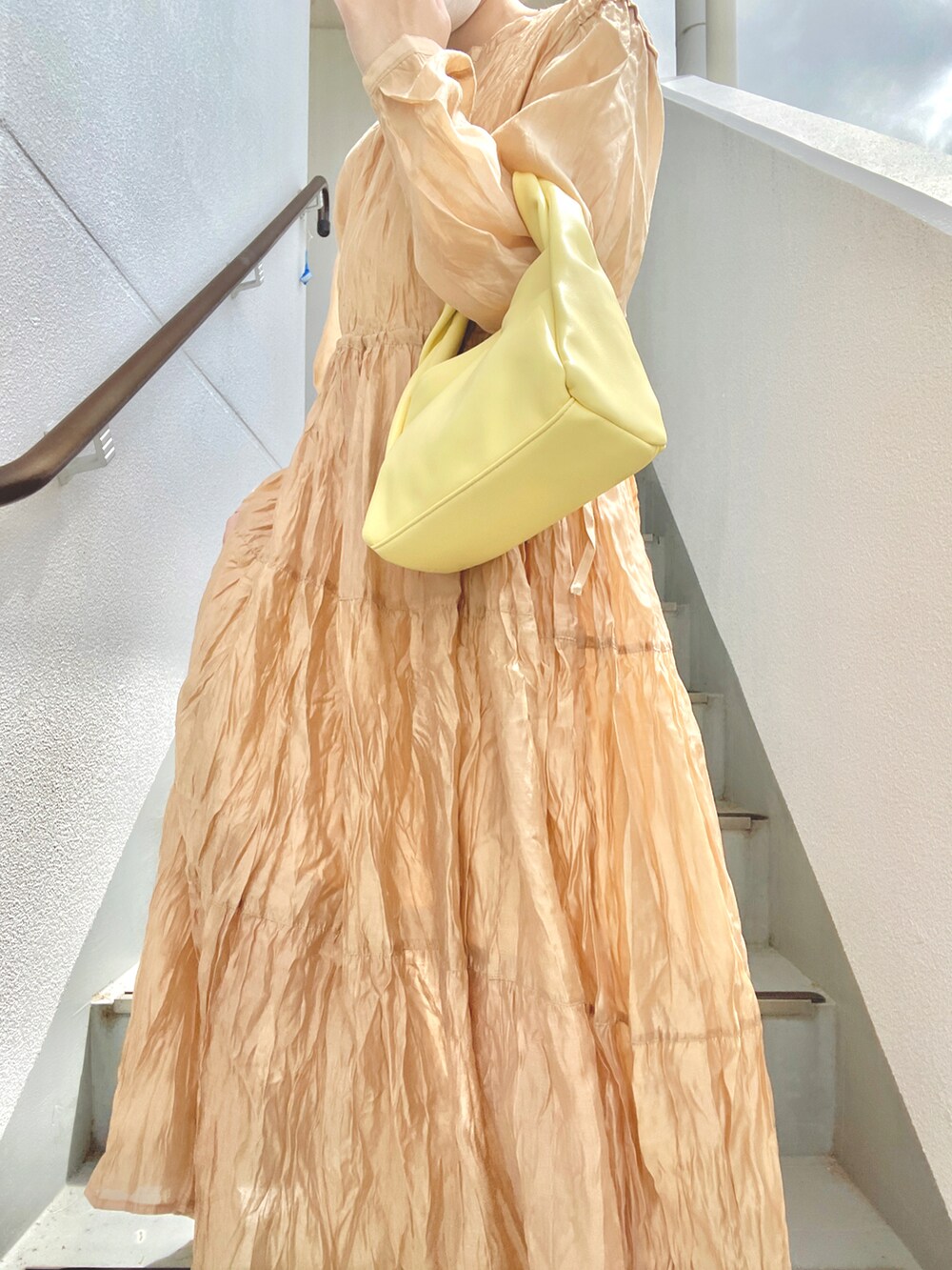 オレンジ系のワンピース、ホワイト系のスニーカーを着用したレディースの夏コーディネートの2枚目の写真