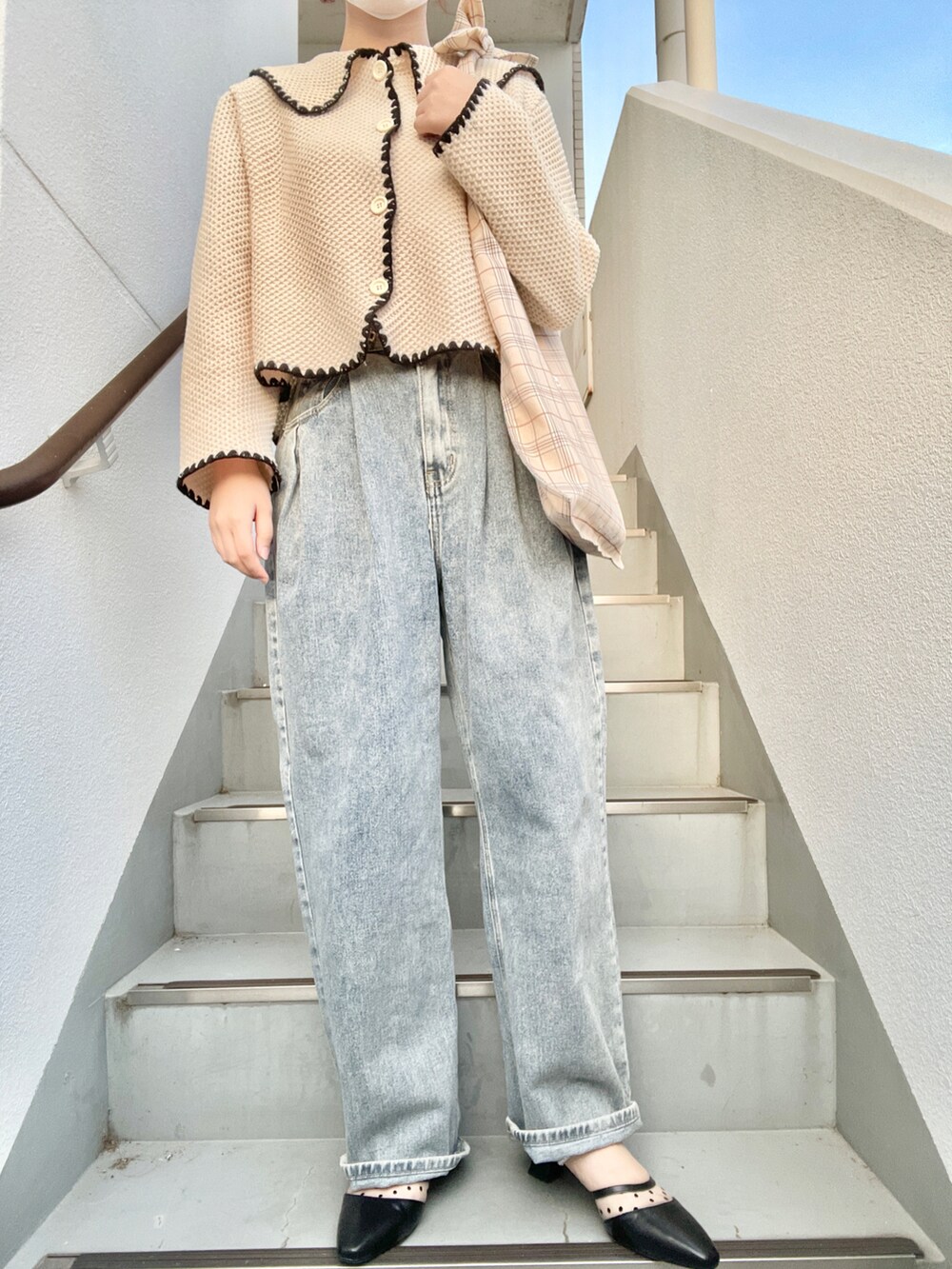 ブルー系のデニムパンツ、ブラック系のパンプス、ベージュ系のトートバッグを着用したレディースの春コーディネートの2枚目の写真