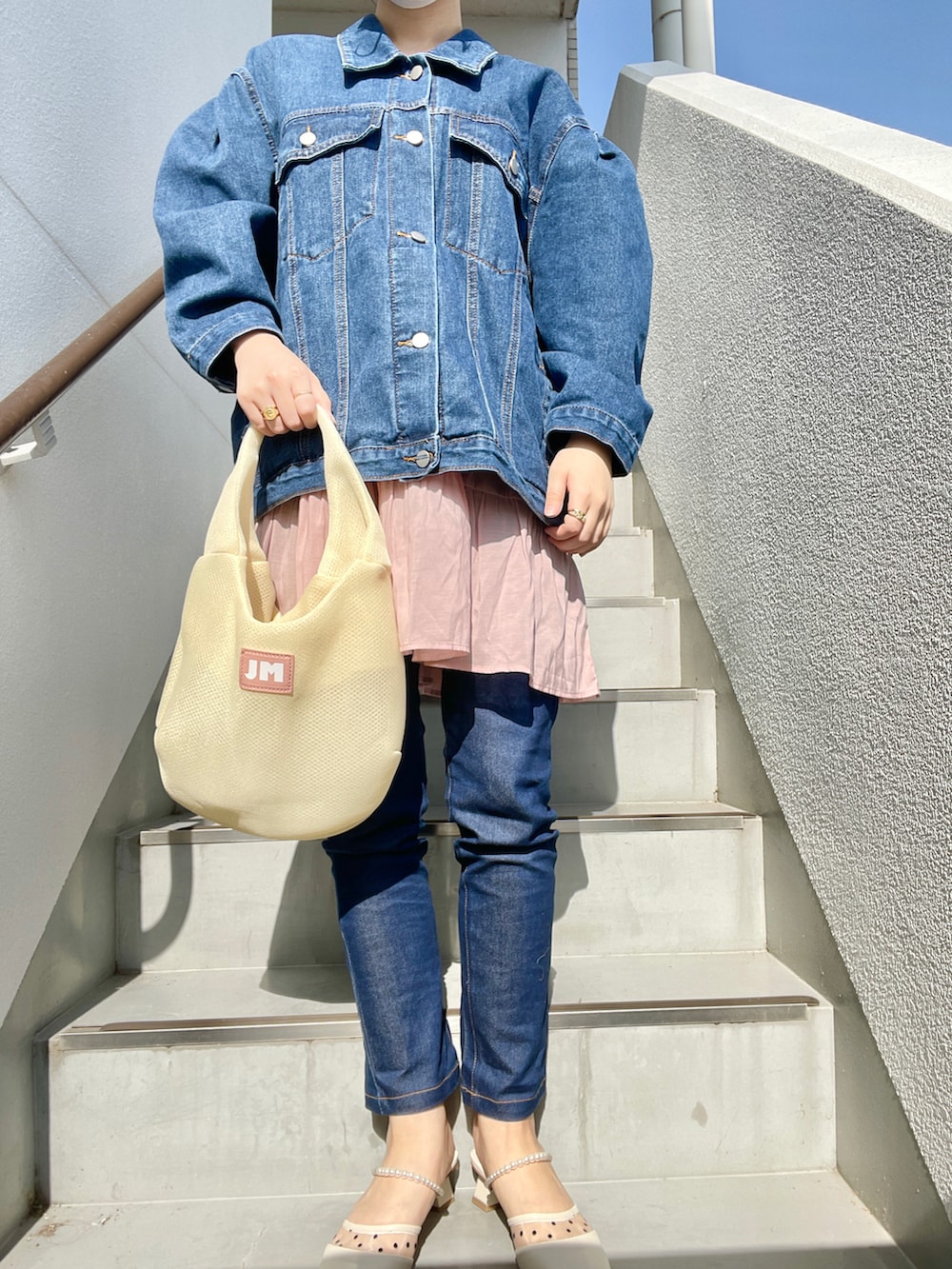 ブルー系のデニムパンツ、その他のハンドバッグ、ホワイト系のパンプスを着用したレディースの春コーディネートの2枚目の写真