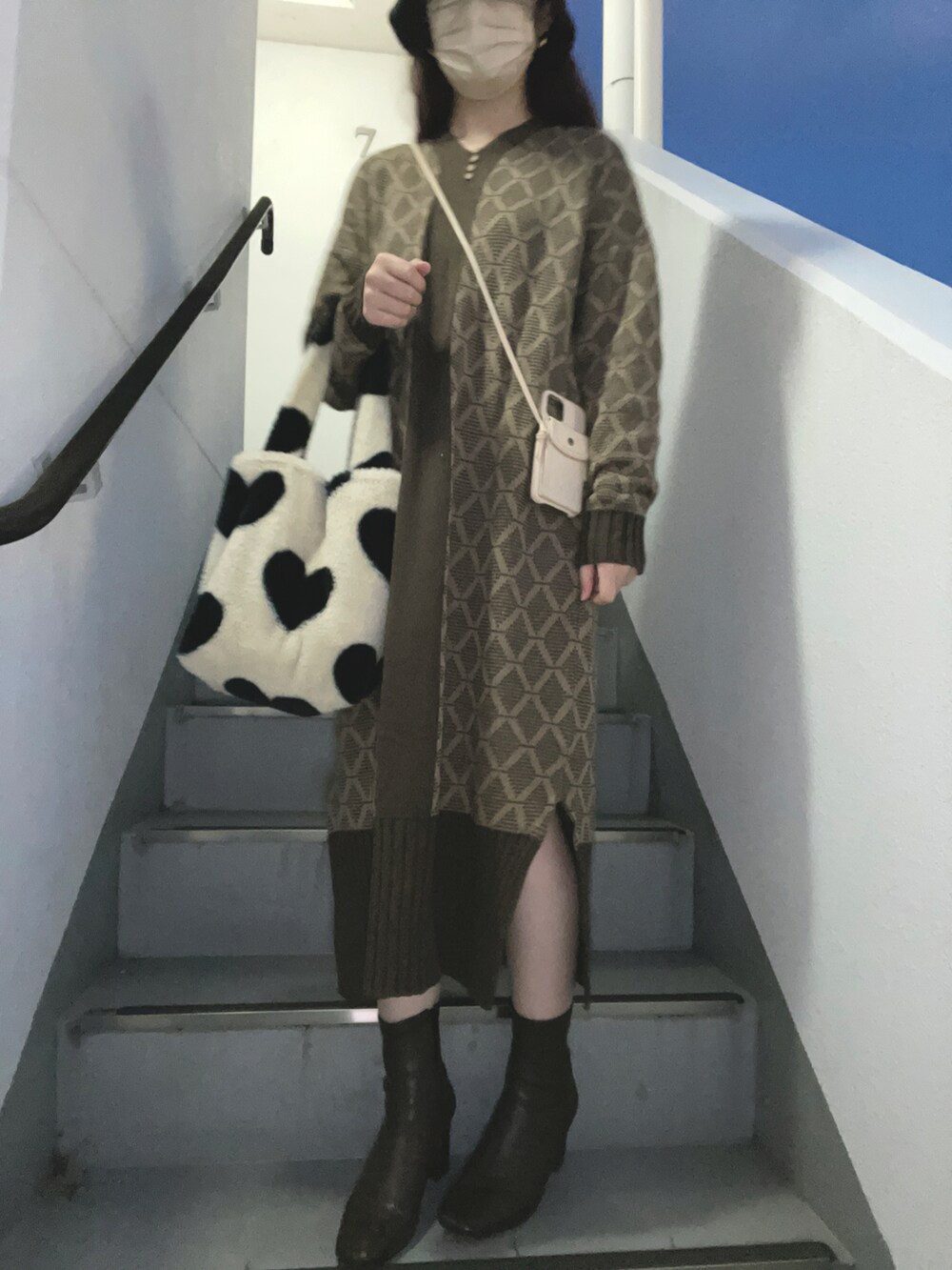 ホワイト系のハンドバッグ、ホワイト系のブーツ、ブラウン系のワンピースを着用したレディースの冬コーディネートの2枚目の写真