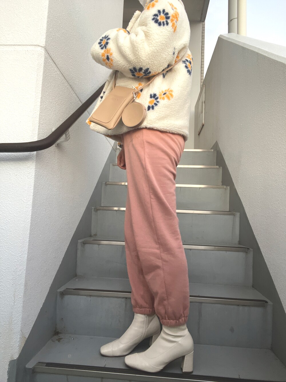 ホワイト系のブルゾン、ベージュ系のショルダーバッグ、ピンク系のスウェットパンツを着用したレディースの冬コーディネートの2枚目の写真