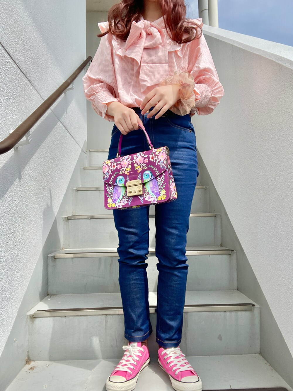ブルー系のデニムパンツ、ピンク系のスニーカー、パープル系のショルダーバッグを着用したレディースの春コーディネートの2枚目の写真