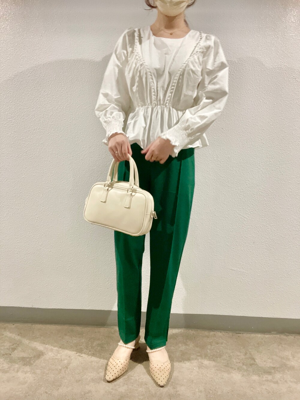 グリーン系のその他パンツ、ベージュ系のパンプス、ホワイト系のハンドバッグを着用したレディースの春コーディネートの2枚目の写真