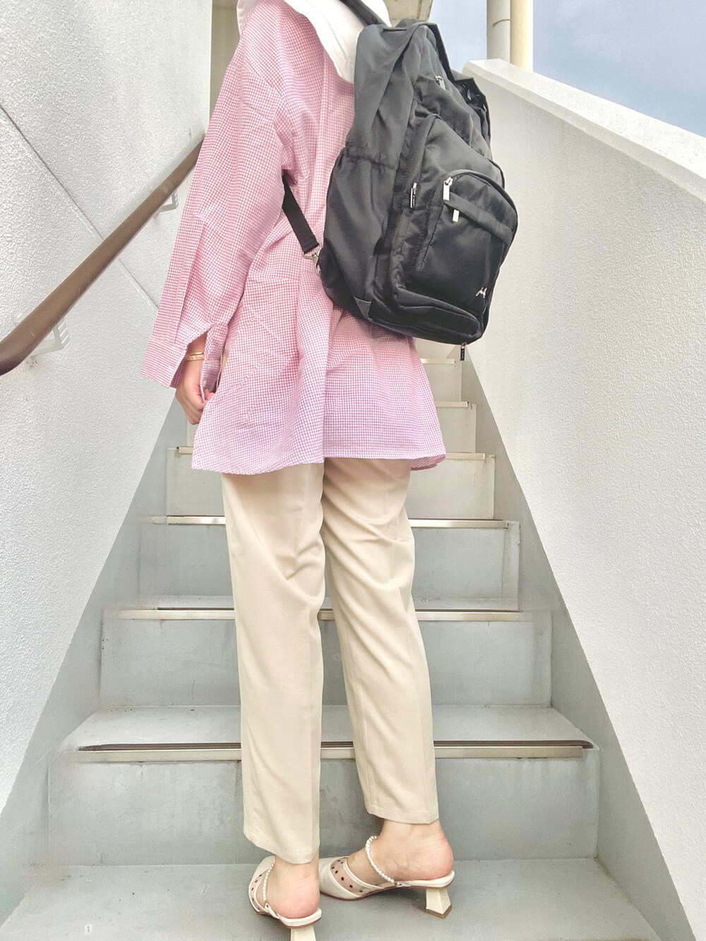 ベージュ系のスラックス、ホワイト系のパンプス、ピンク系のシャツ/ブラウスを着用したレディースの夏コーディネートの2枚目の写真