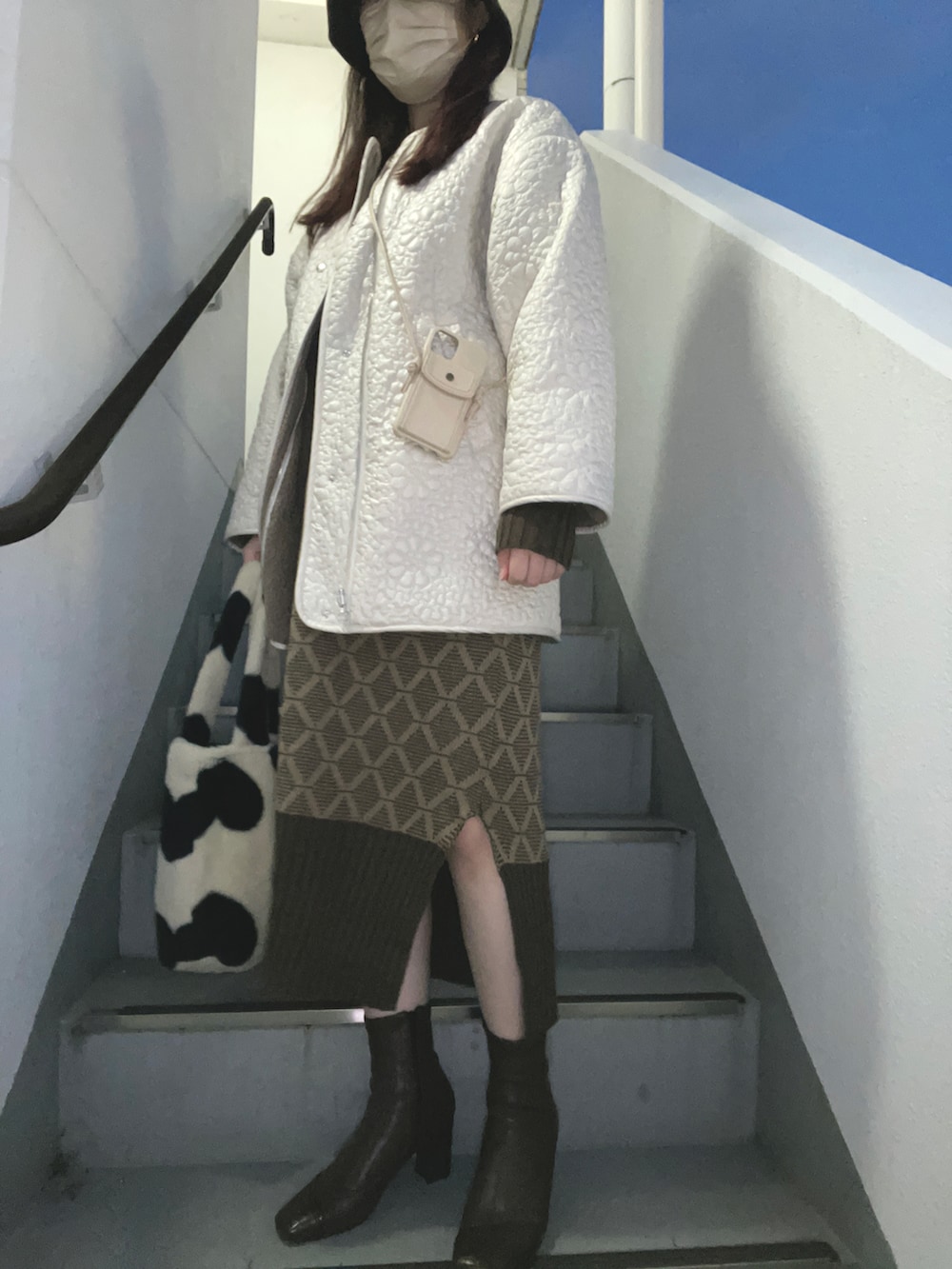 ホワイト系のハンドバッグ、ホワイト系のブーツ、ブラウン系のワンピースを着用したレディースの冬コーディネートの2枚目の写真