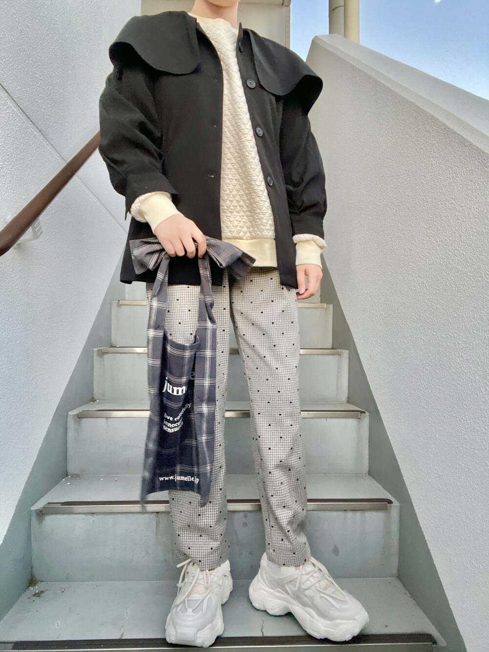 グレー系のトートバッグ、グレー系のパンツ、ホワイト系のスニーカーを着用したレディースの春コーディネートの2枚目の写真