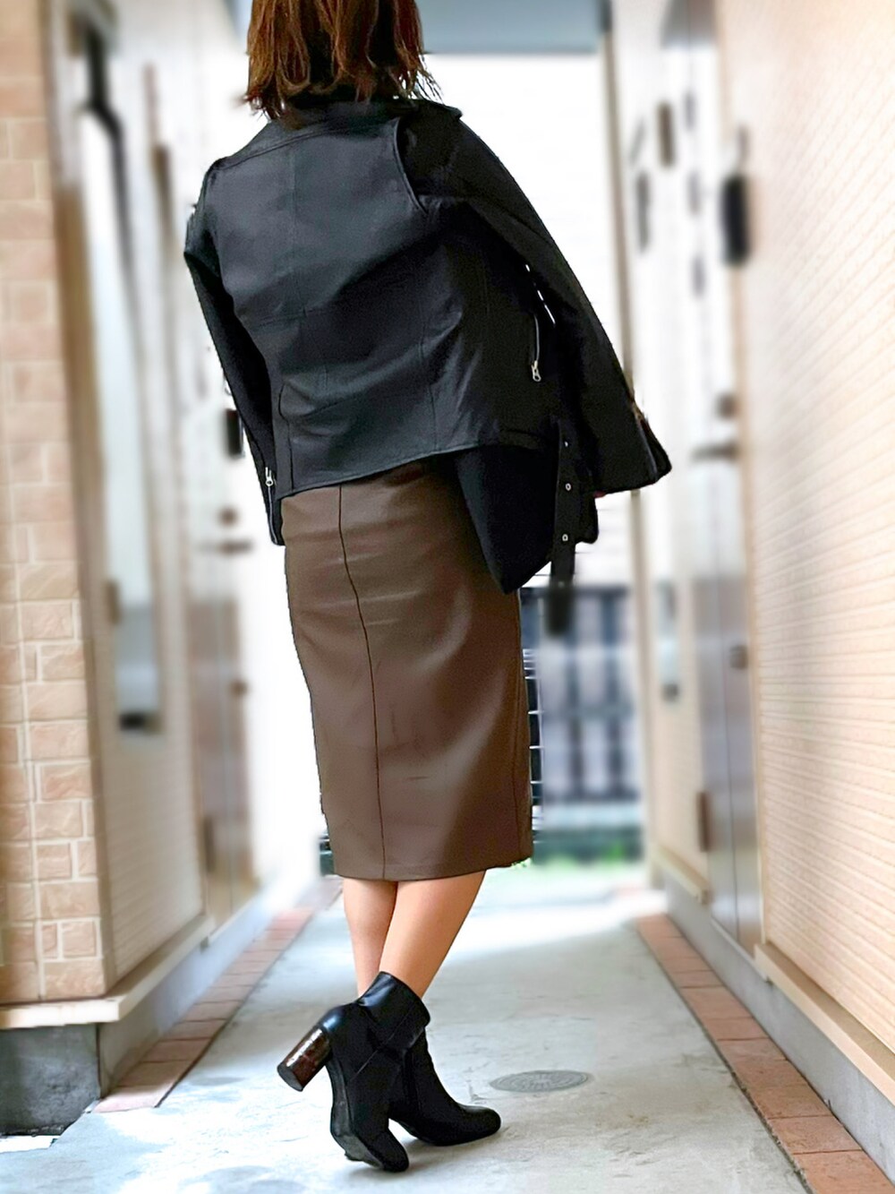 ブラック系のニット/セーター、ブラウン系のスカート、ブラック系のトートバッグを着用したレディースの春コーディネートの3枚目の写真