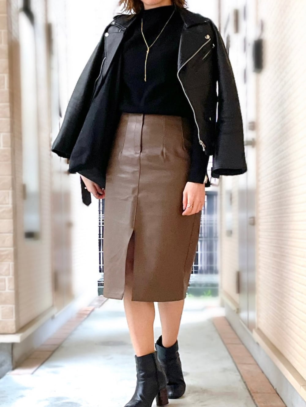 ブラック系のニット/セーター、ブラウン系のスカート、ブラック系のトートバッグを着用したレディースの春コーディネートの2枚目の写真