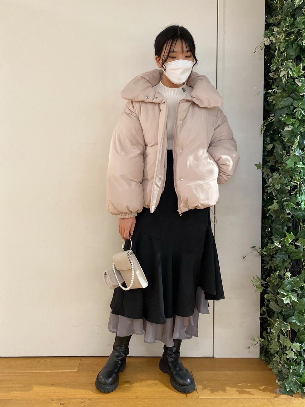 ホワイト系のニット/セーター、ピンク系のダウンジャケット/コート、ブラック系のスカートを着用したレディースの冬コーディネートの3枚目の写真
