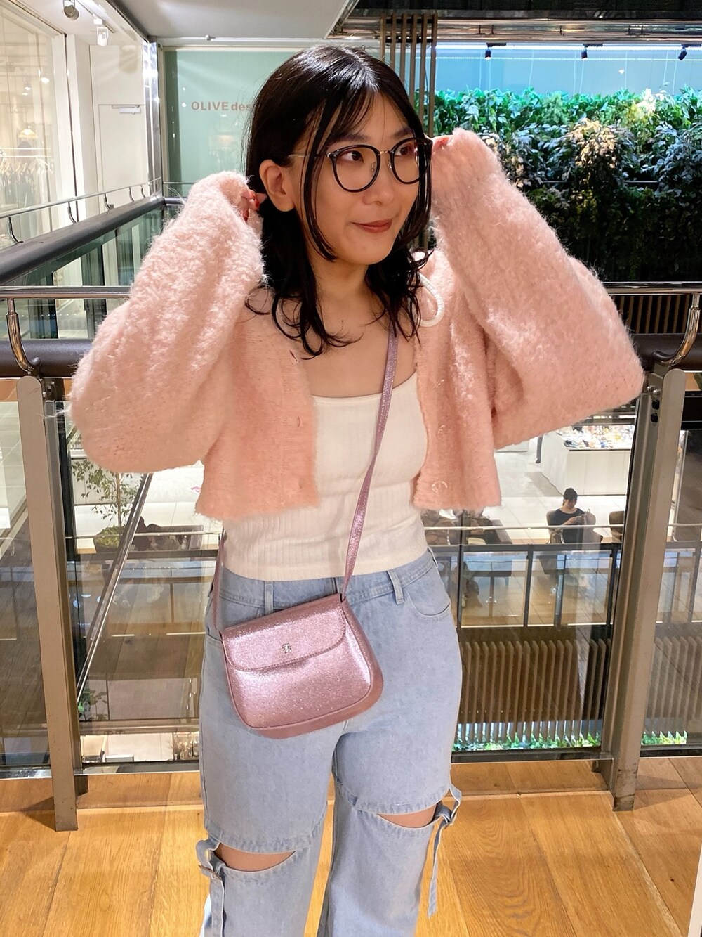 ピンク系のカーディガン/ボレロ、ホワイト系のキャミソール、ブルー系のデニムパンツを着用したレディースの秋コーディネートの2枚目の写真