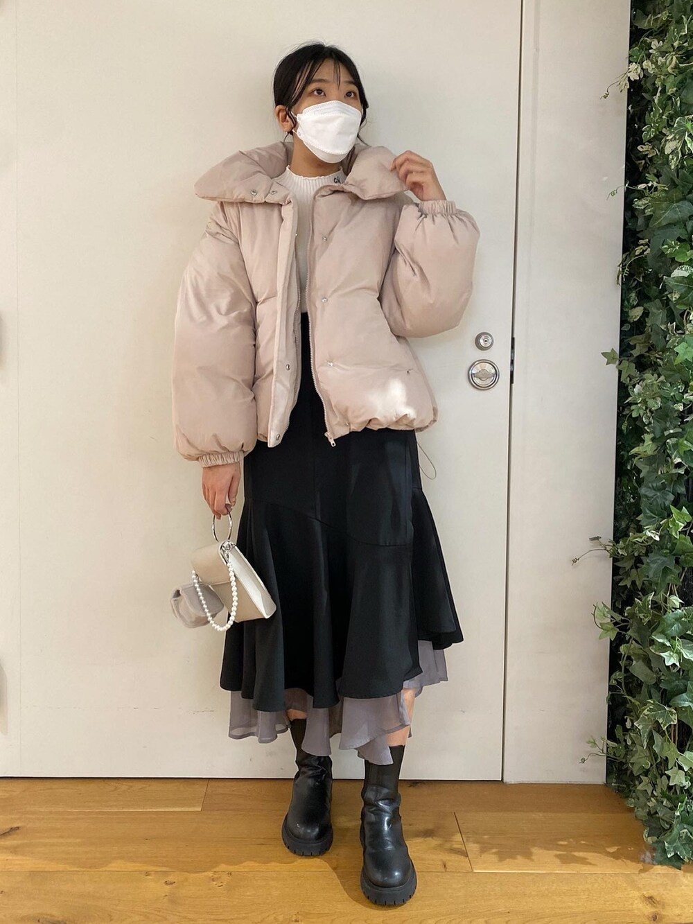 ホワイト系のニット/セーター、ピンク系のダウンジャケット/コート、ブラック系のスカートを着用したレディースの冬コーディネートの2枚目の写真