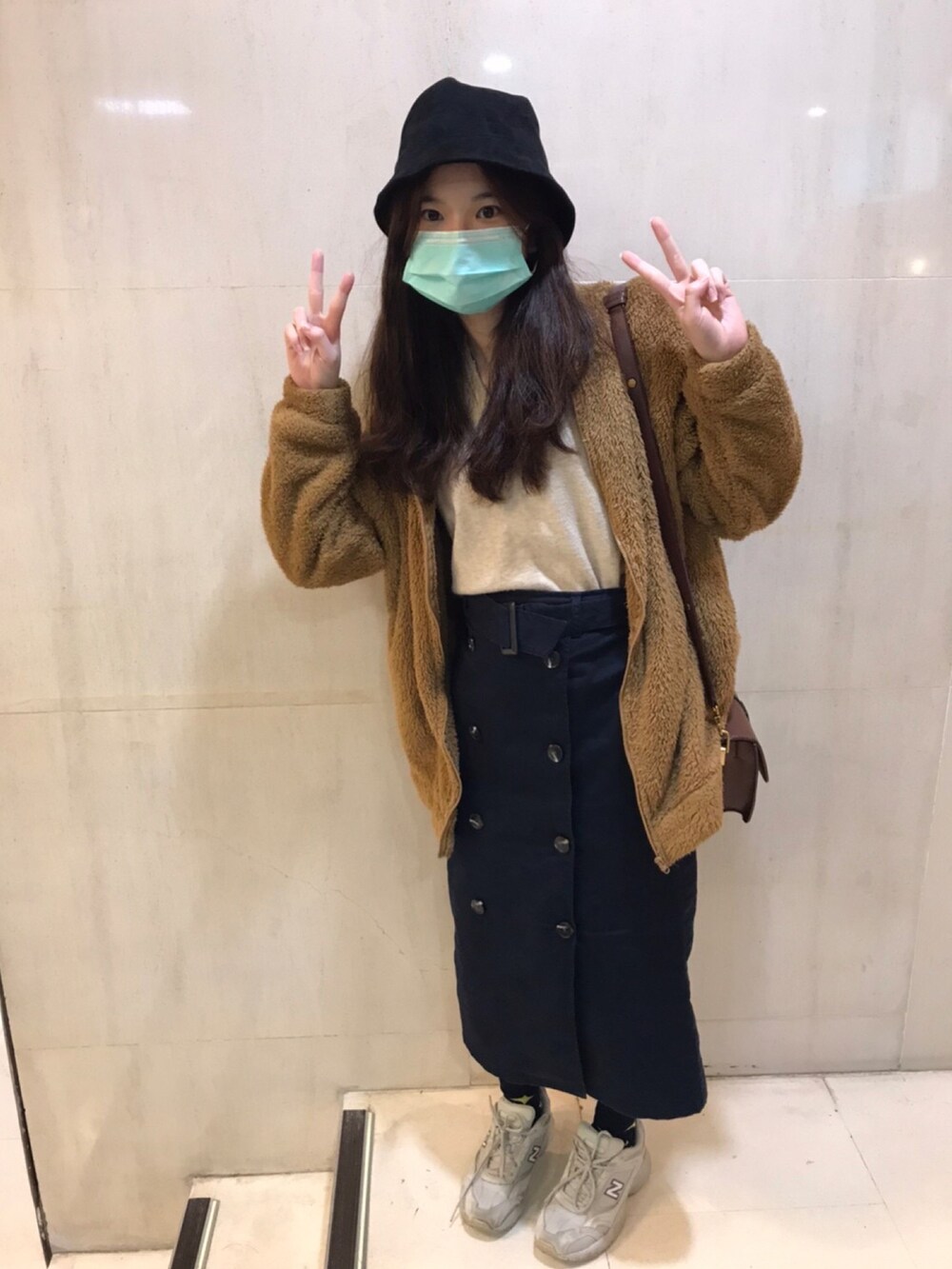 ブルー系のスカート、ベージュ系のベスト、ブラウン系のノーカラージャケットを着用したレディースの秋コーディネートの2枚目の写真