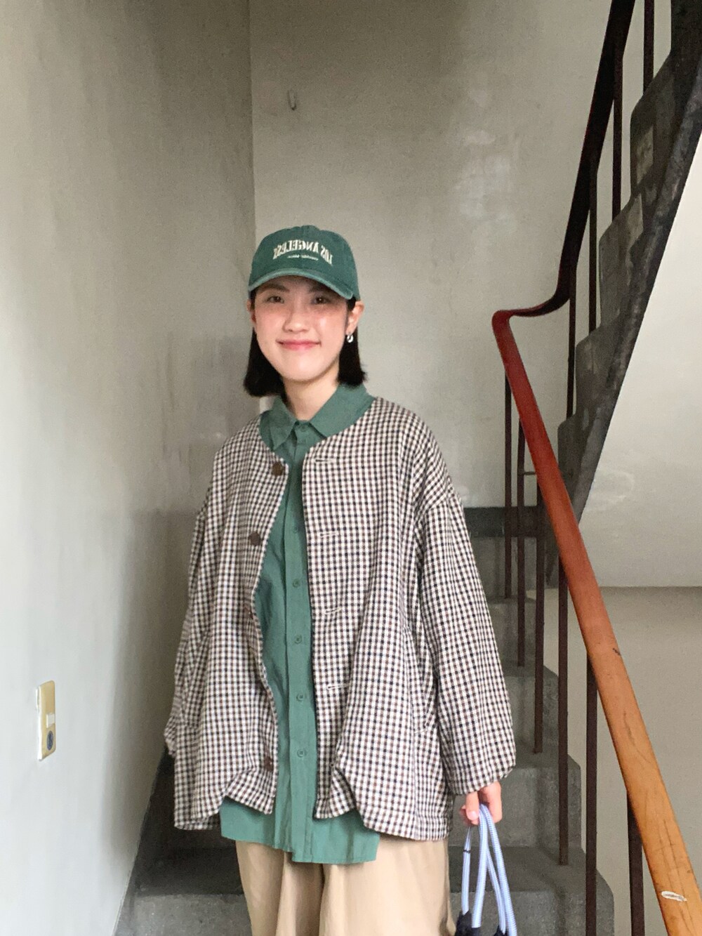 ベージュ系のチノパンツ、グレー系のスニーカー、グリーン系のシャツ/ブラウスを着用したレディースの春コーディネートの3枚目の写真