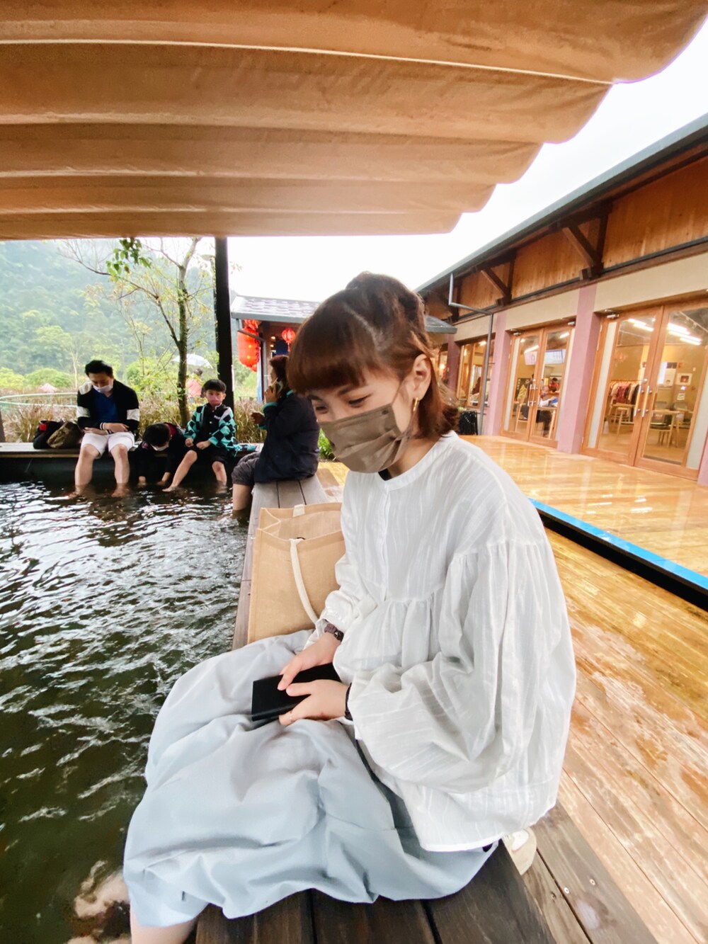 ベージュ系のショルダーバッグ、ベージュ系のスニーカー、ブルー系のチノパンツを着用したレディースの春コーディネートの2枚目の写真