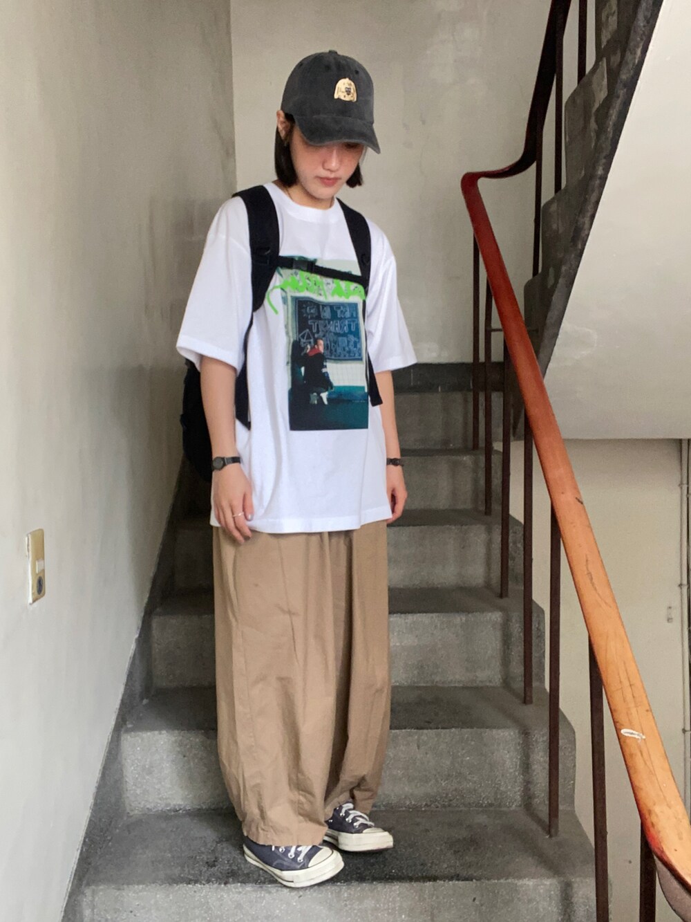 ホワイト系のTシャツ/カットソー、ブラウン系のチノパンツ、グレー系のスニーカーを着用したレディースの春コーディネートの2枚目の写真