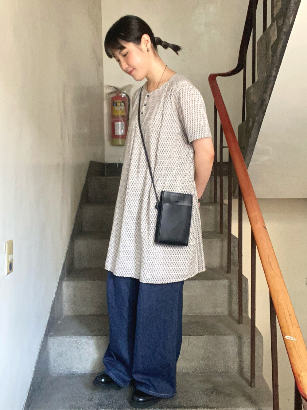 ブラック系のショルダーバッグ、ブルー系のデニムパンツを着用したレディースの夏コーディネートの2枚目の写真