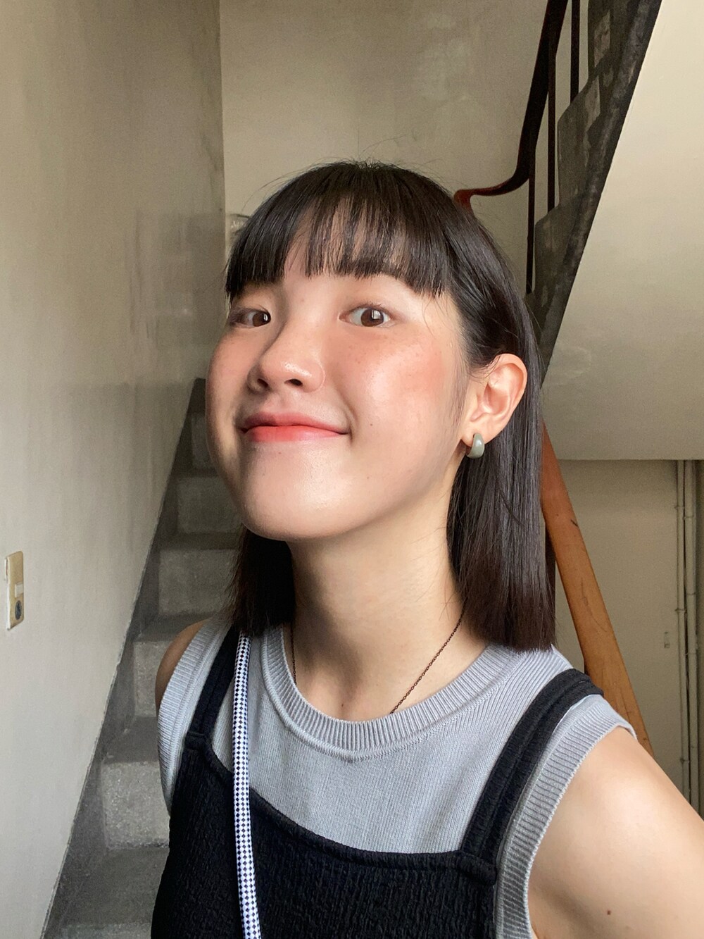 ブラック系のキャミソール、グレー系のチノパンツ、ブラック系のスニーカーを着用したレディースの夏コーディネートの2枚目の写真