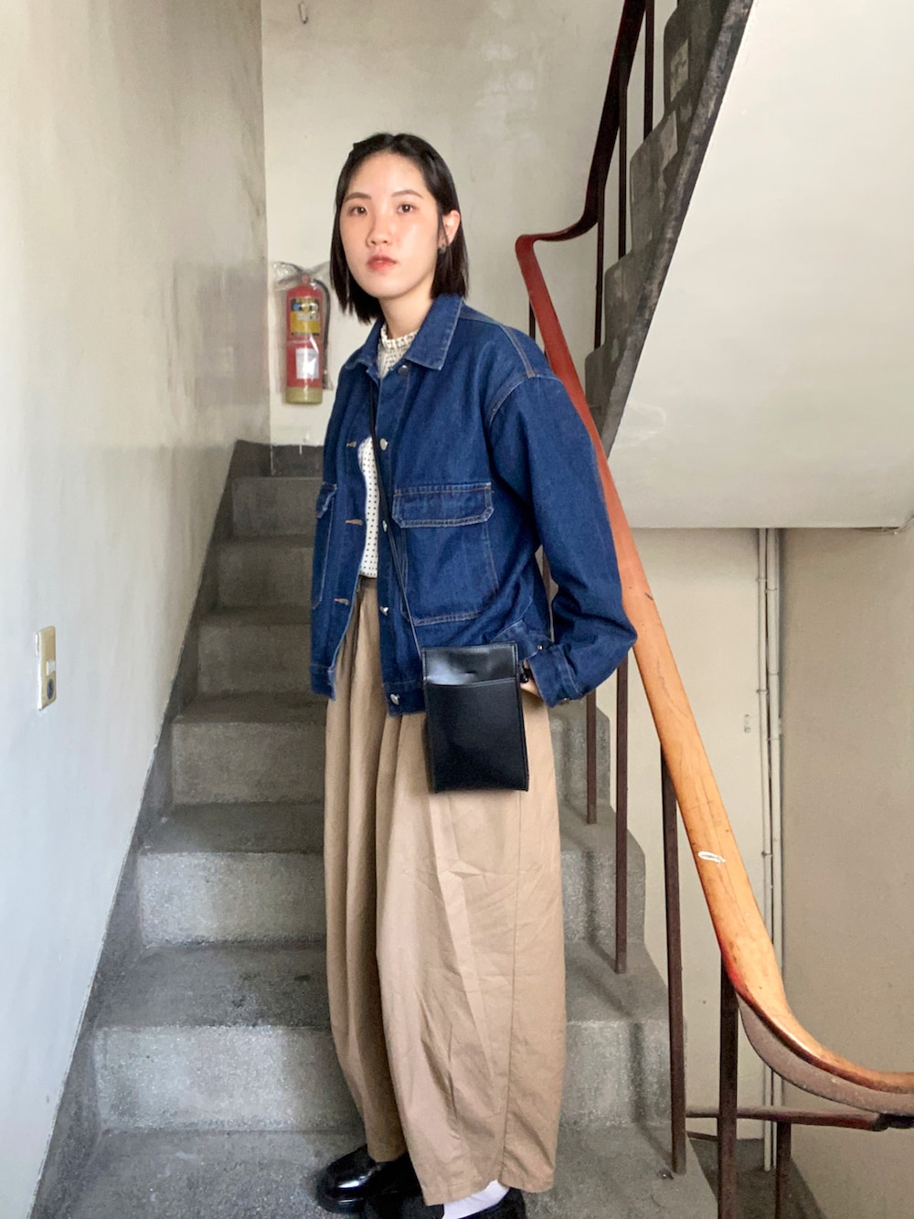 ブルー系のデニムジャケット、ブラック系のショルダーバッグ、ベージュ系のシャツ/ブラウスを着用したレディースの春コーディネートの2枚目の写真