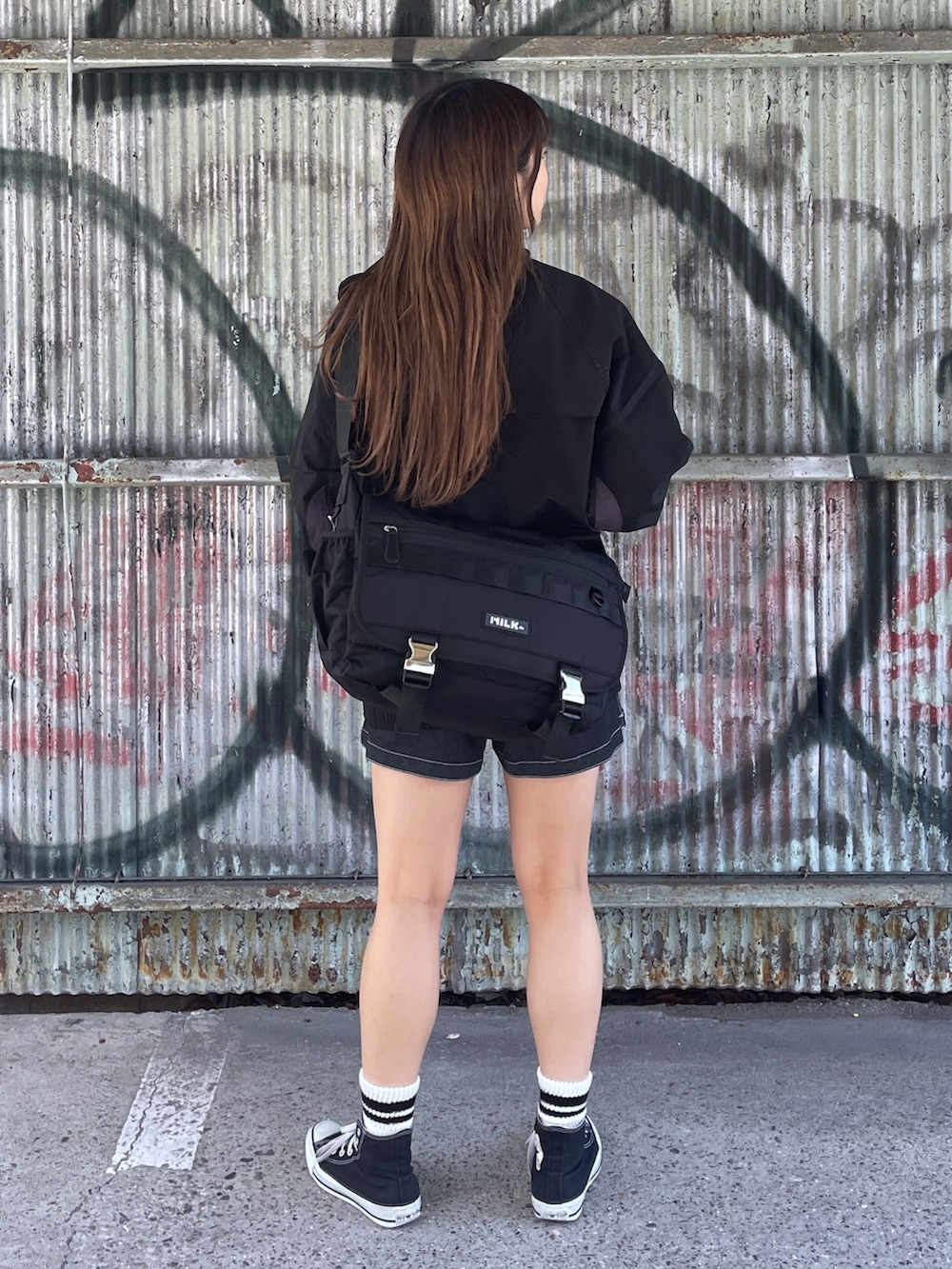 ブラック系のブルゾン、ブラック系のデニムパンツ、ブラック系のメッセンジャーバッグを着用したレディースの春コーディネートの2枚目の写真