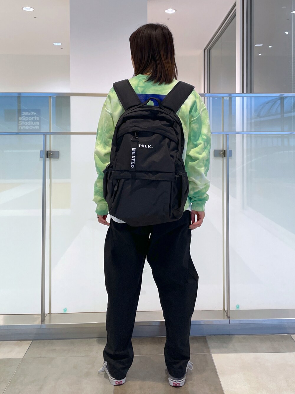 ブラック系のその他パンツ、グリーン系のスウェット、レッド系のバックパック/リュックを着用したレディースの春コーディネートの2枚目の写真