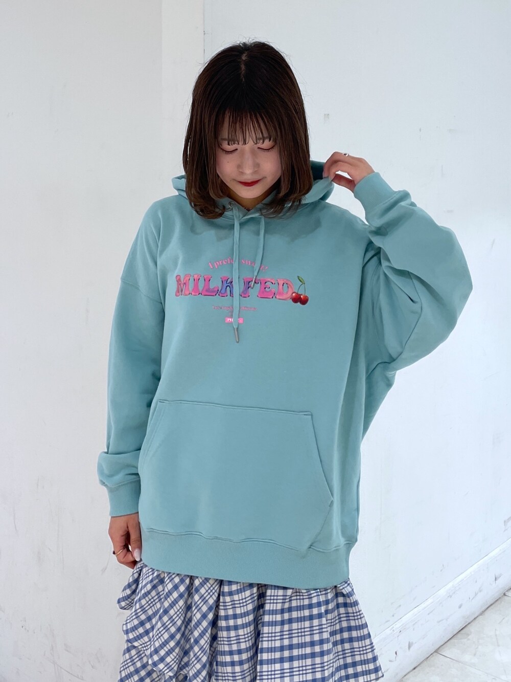 グリーン系のパーカー、ブルー系のスカート、シルバー系のショルダーバッグを着用したレディースの冬コーディネートの3枚目の写真