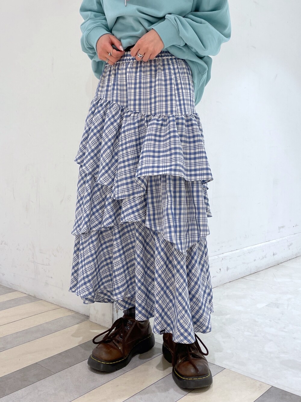 グリーン系のパーカー、ブルー系のスカート、シルバー系のショルダーバッグを着用したレディースの冬コーディネートの4枚目の写真