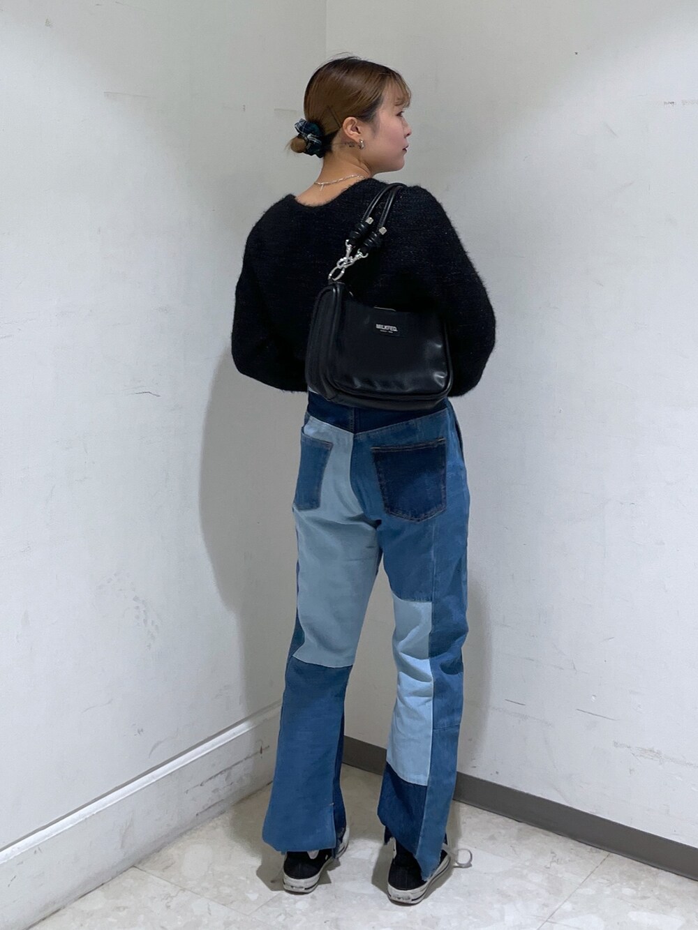 ブルー系のデニムパンツ、ブラック系のカーディガン/ボレロ、ブラック系のショルダーバッグを着用したレディースの冬コーディネートの2枚目の写真