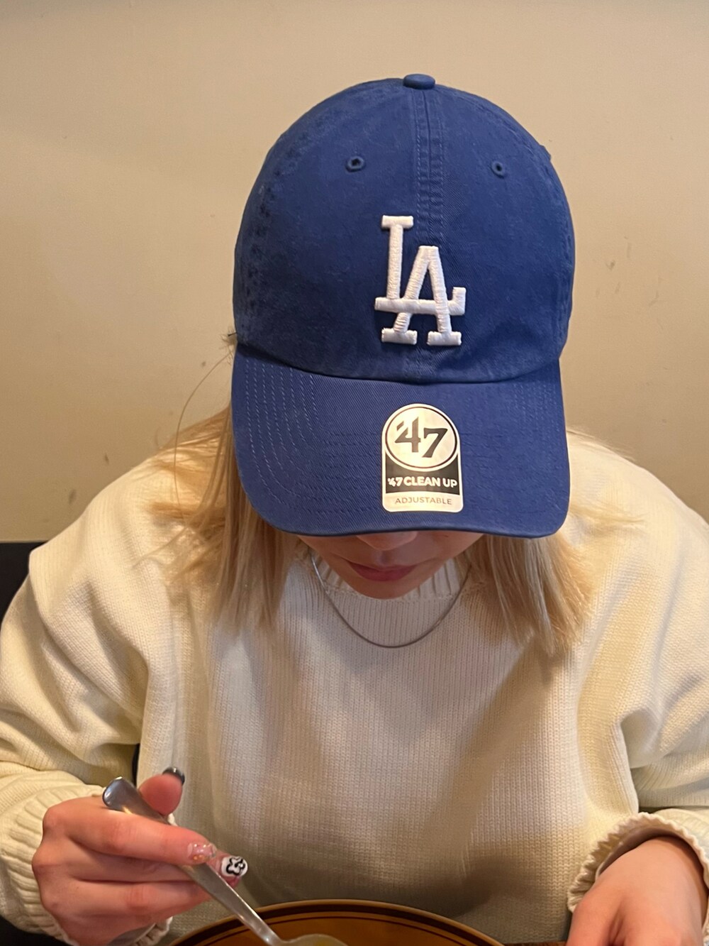 ブルー系のキャップを着用したレディースの春コーディネートの2枚目の写真