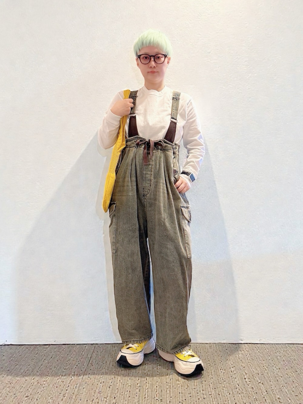 イエロー系のスニーカー、ブラウン系のデニムパンツ、イエロー系のトートバッグを着用したレディースの冬コーディネートの5枚目の写真