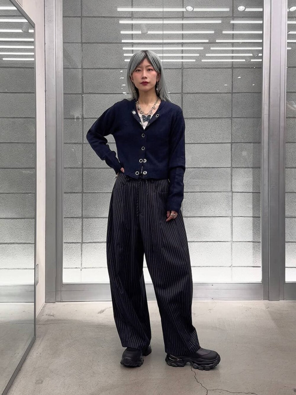 ホワイト系のTシャツ/カットソー、ブラック系のブーツ、ブルー系のスラックスを着用したレディースの冬コーディネートの7枚目の写真