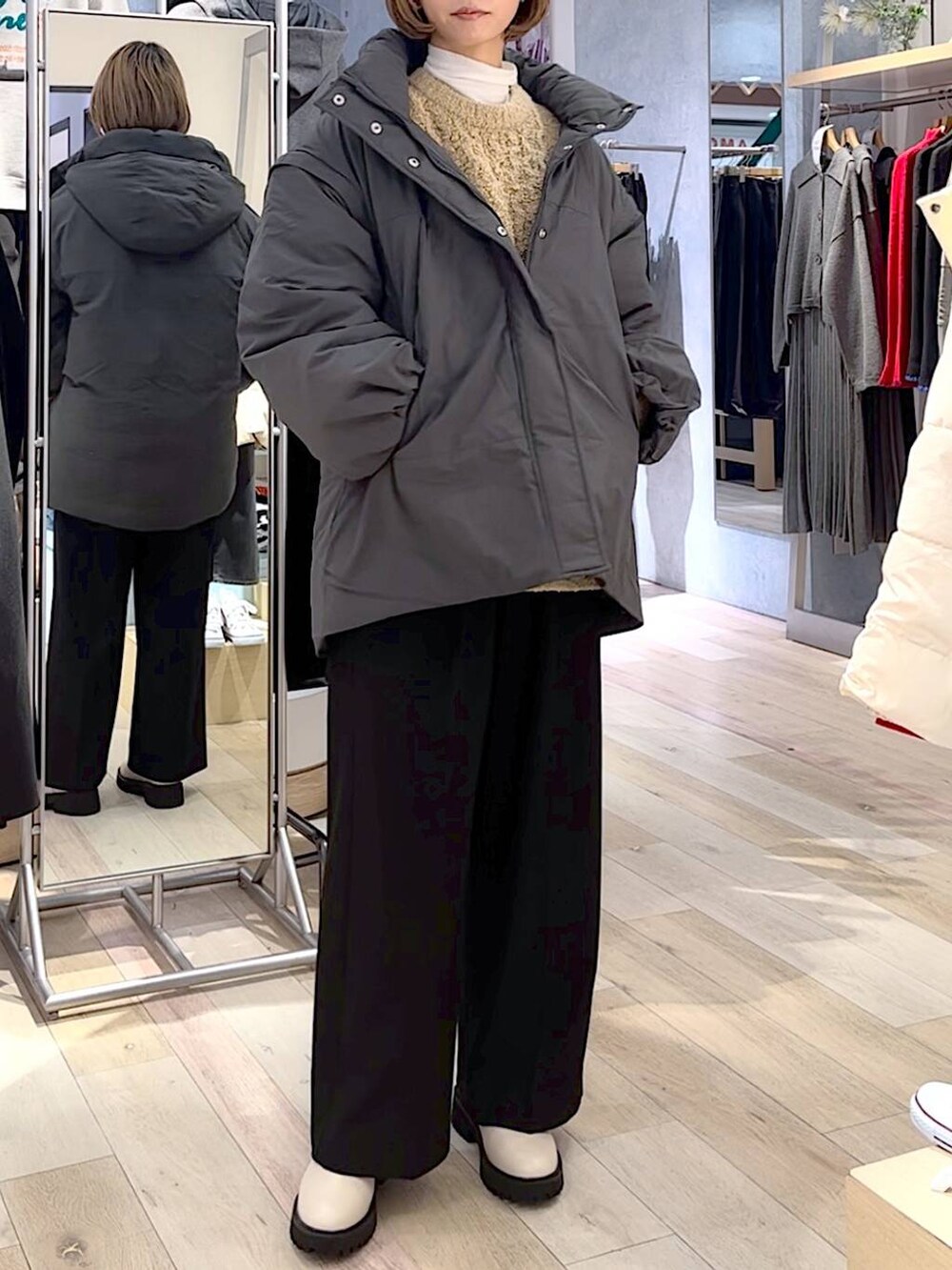 グレー系のダウンジャケット/コート、ホワイト系のブーツ、ブラック系のスラックスを着用したレディースの秋コーディネートの2枚目の写真