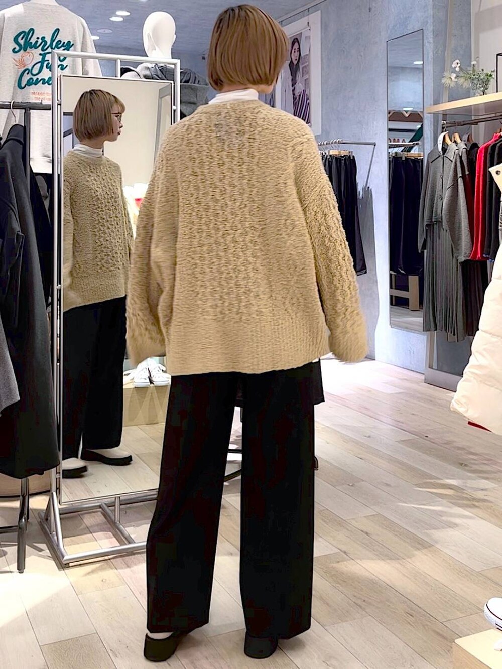 グレー系のダウンジャケット/コート、ホワイト系のブーツ、ブラック系のスラックスを着用したレディースの秋コーディネートの5枚目の写真