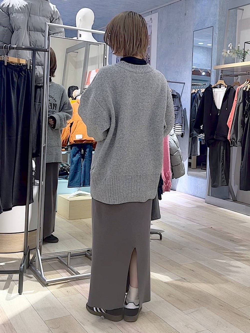 ブラック系のスニーカー、グレー系のスカート、グレー系のニット/セーターを着用したレディースの冬コーディネートの2枚目の写真