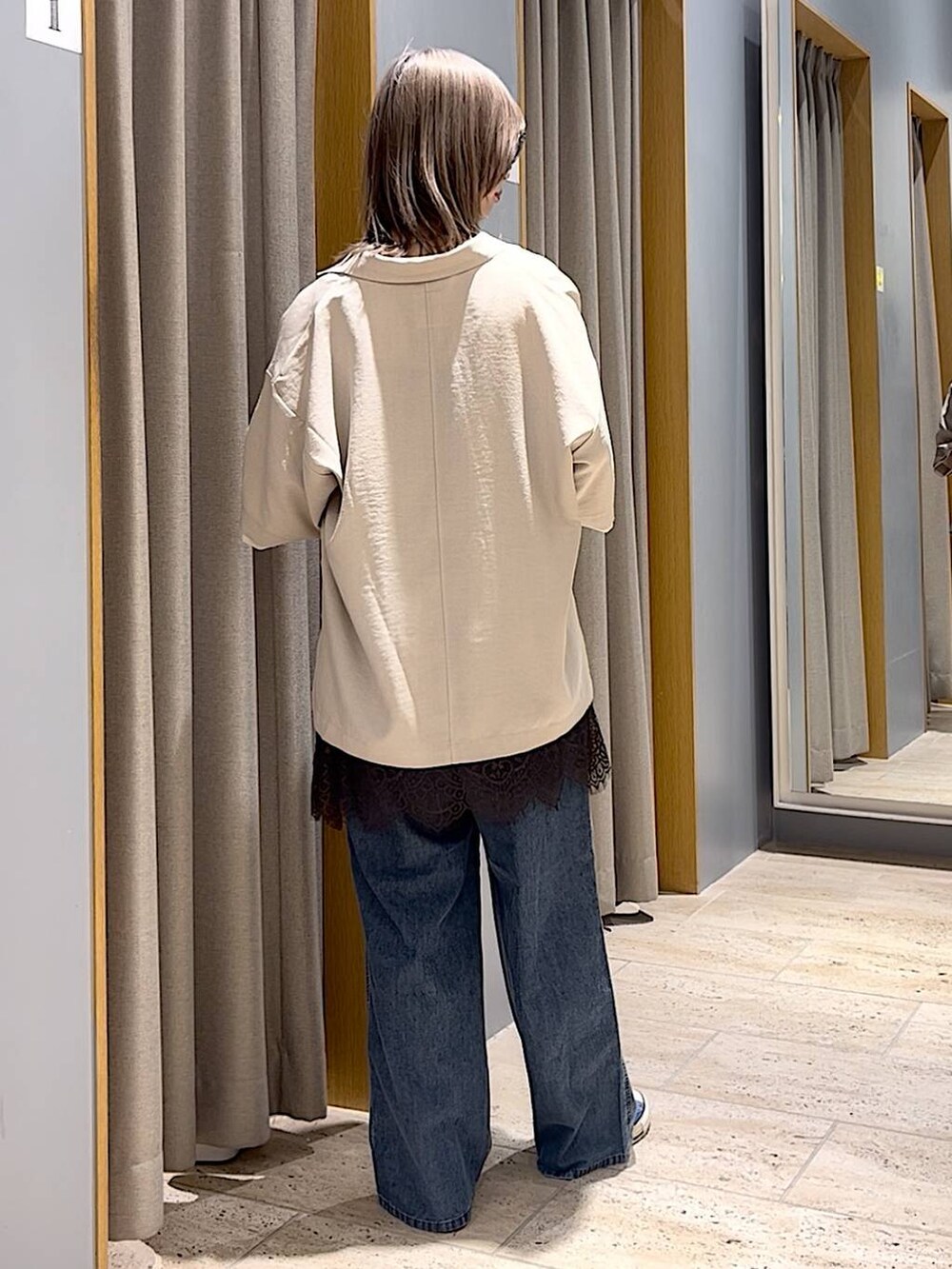 ブルー系のスニーカー、ブルー系のデニムパンツ、ベージュ系のテーラードジャケットを着用したレディースの春コーディネートの2枚目の写真
