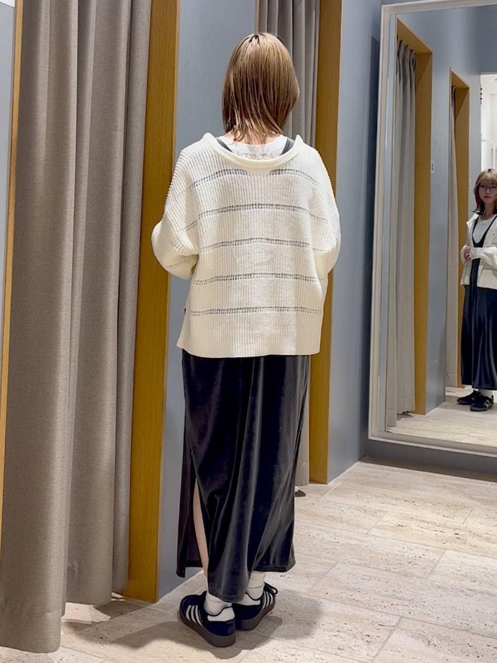 ブラック系のスニーカー、グレー系のジャンパースカート、ゴールド系のチョーカーを着用したレディースの冬コーディネートの2枚目の写真