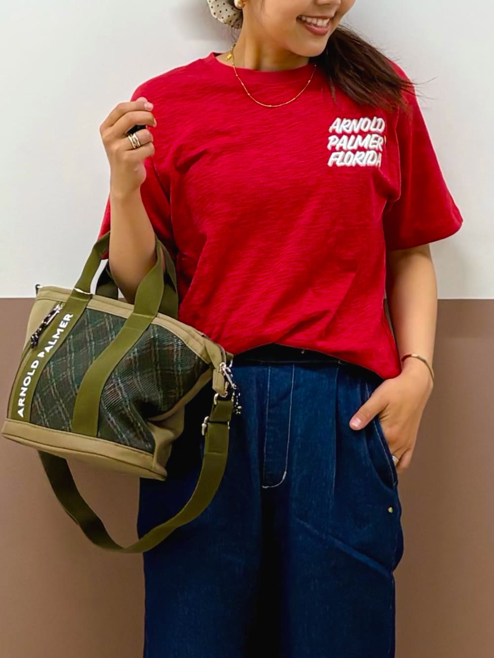レッド系のTシャツ/カットソー、ブルー系のデニムパンツ、グリーン系のショルダーバッグを着用したレディースの夏コーディネートの2枚目の写真