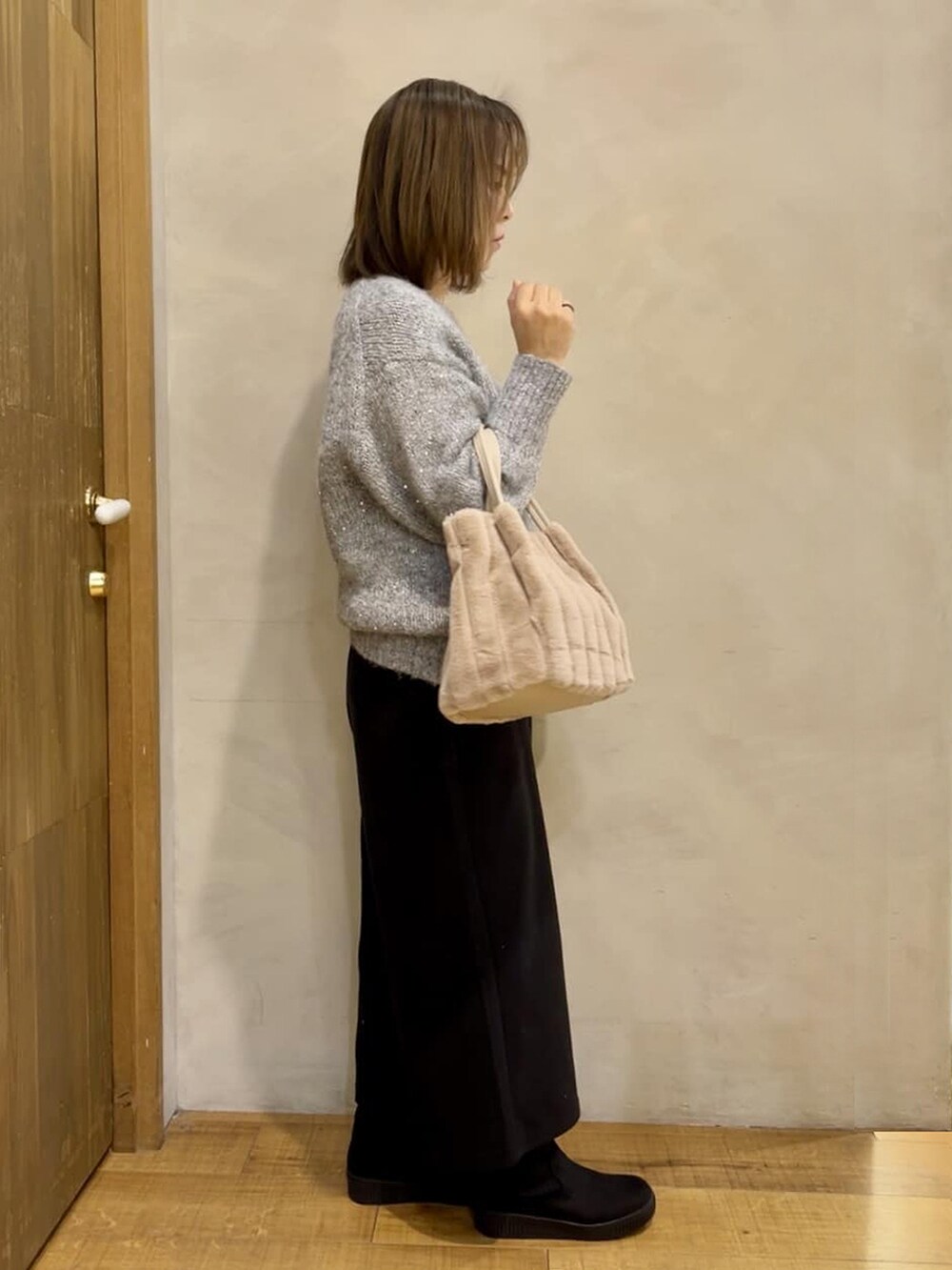 グレー系のニット/セーター、ブラック系のブーツ、ベージュ系のトートバッグを着用したレディースの冬コーディネートの2枚目の写真