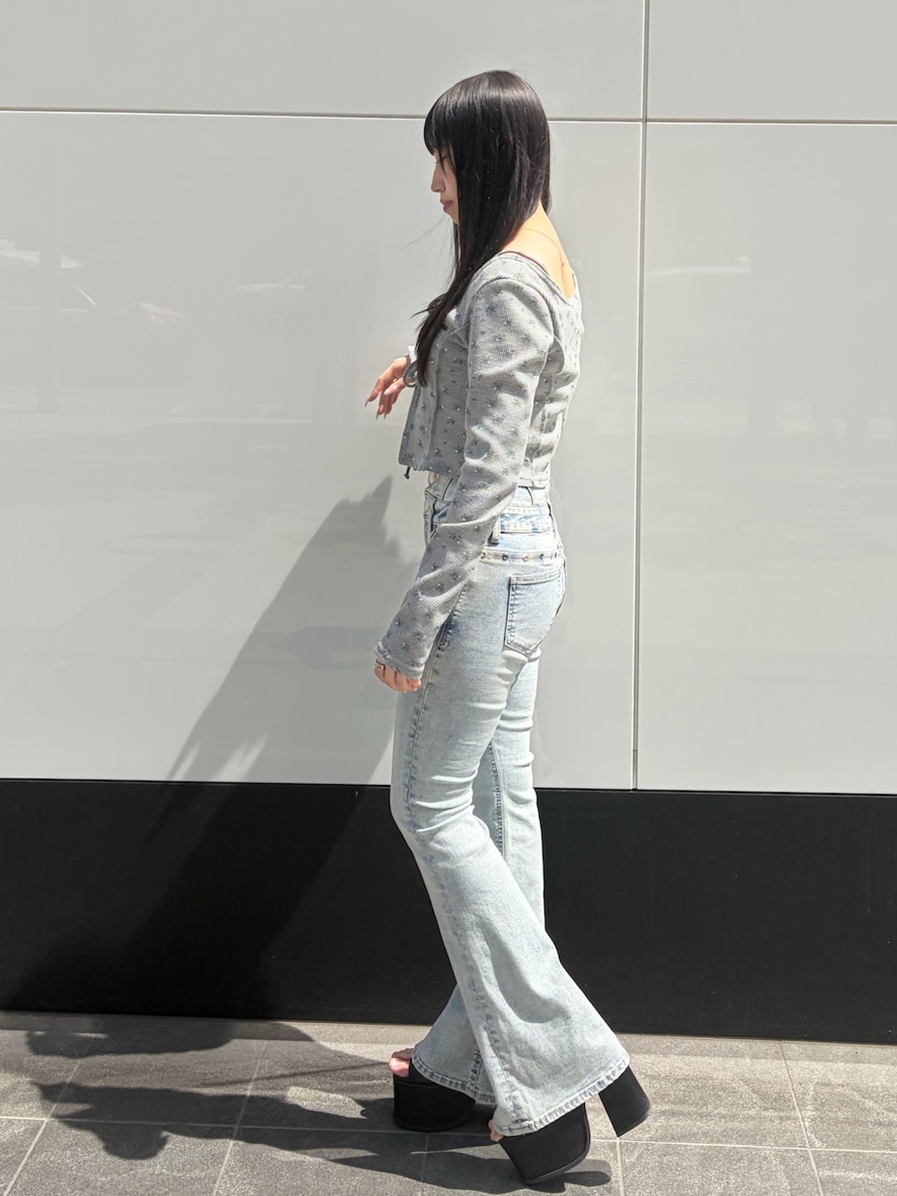 グレー系のTシャツ/カットソー、ブルー系のデニムパンツ、ブラック系のサンダルを着用したレディースの春コーディネートの2枚目の写真