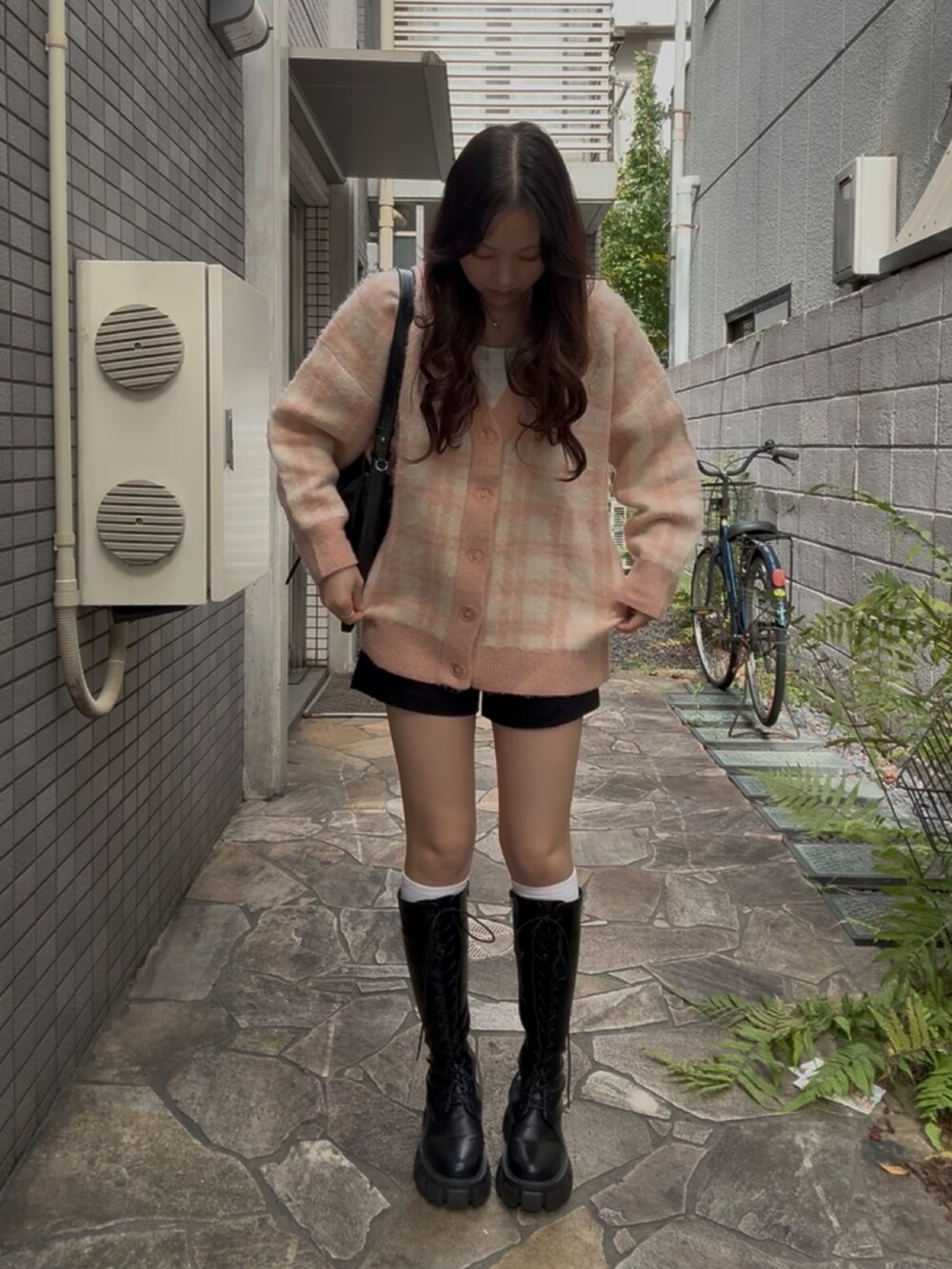 ブラック系のブーツ、ピンク系のカーディガン/ボレロを着用したレディースの冬コーディネートの2枚目の写真