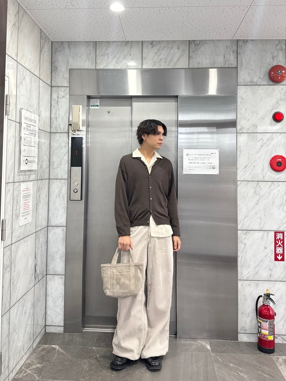 ブラウン系のニット/セーター、ベージュ系のハンドバッグ、ベージュ系のその他パンツを着用したメンズの春コーディネートの2枚目の写真