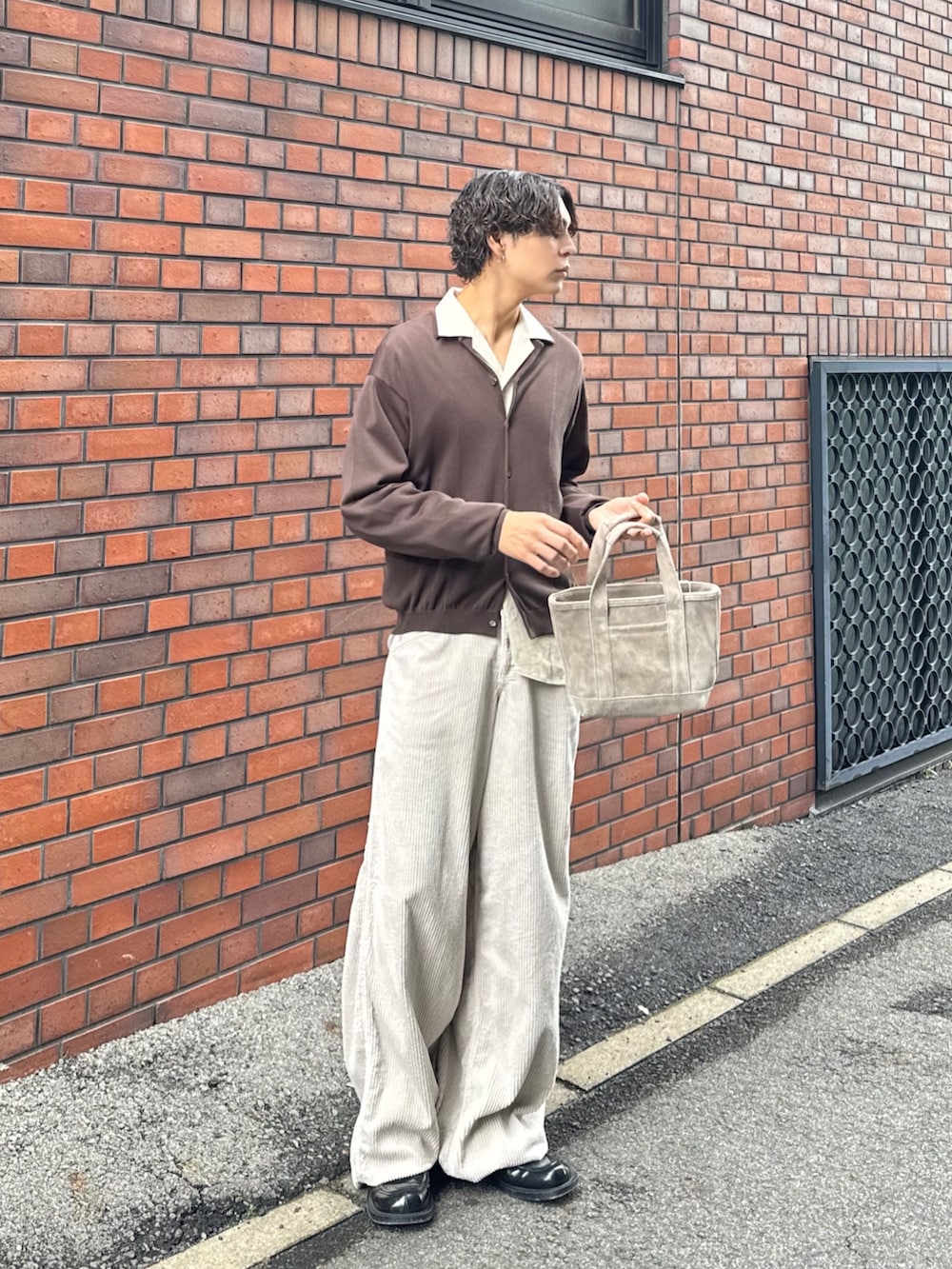 ブラウン系のニット/セーター、ベージュ系のハンドバッグ、ベージュ系のその他パンツを着用したメンズの春コーディネートの5枚目の写真